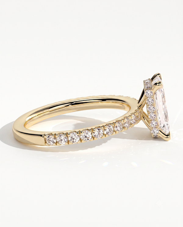 color_10K_YG, color_14K_YG &&A close-up side view of a yellow gold ring featuring a large rectangular clear gemstone in a halo setting, with a pave band accented by smaller round stones, set against a clean white background.