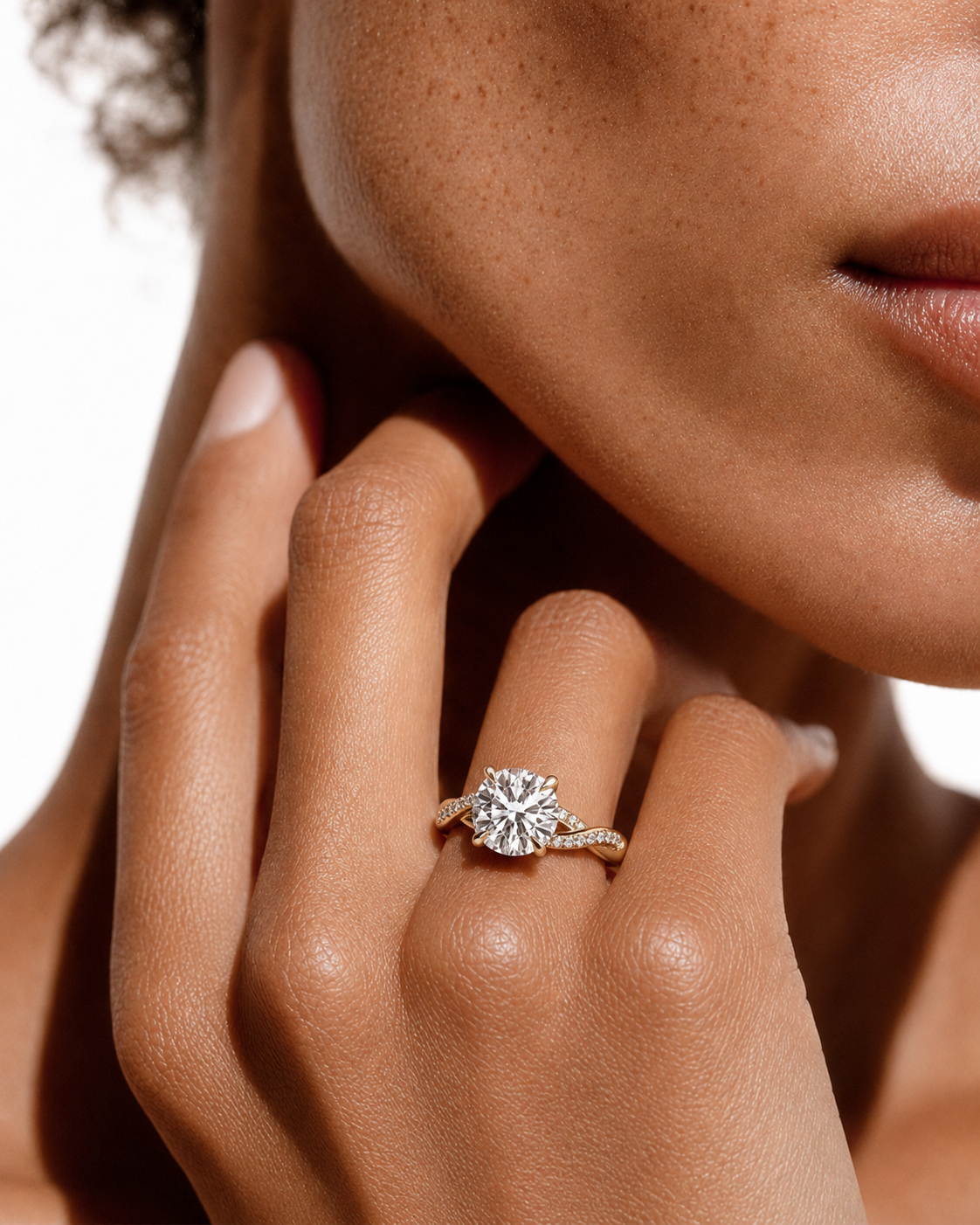 color_10K_YG, color_14K_YG &&
A close-up lifestyle shot of a model wearing a yellow gold engagement ring with a round-cut diamond. The ring is shown on her finger, with her hand and face visible against a clean white background.