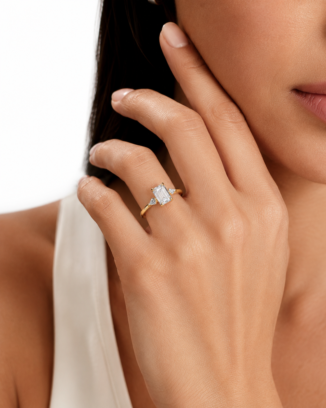 color_10K_YG, color_14K_YG &&
A close-up lifestyle shot of a model wearing a yellow gold ring with a rectangular clear gemstone on her finger.
