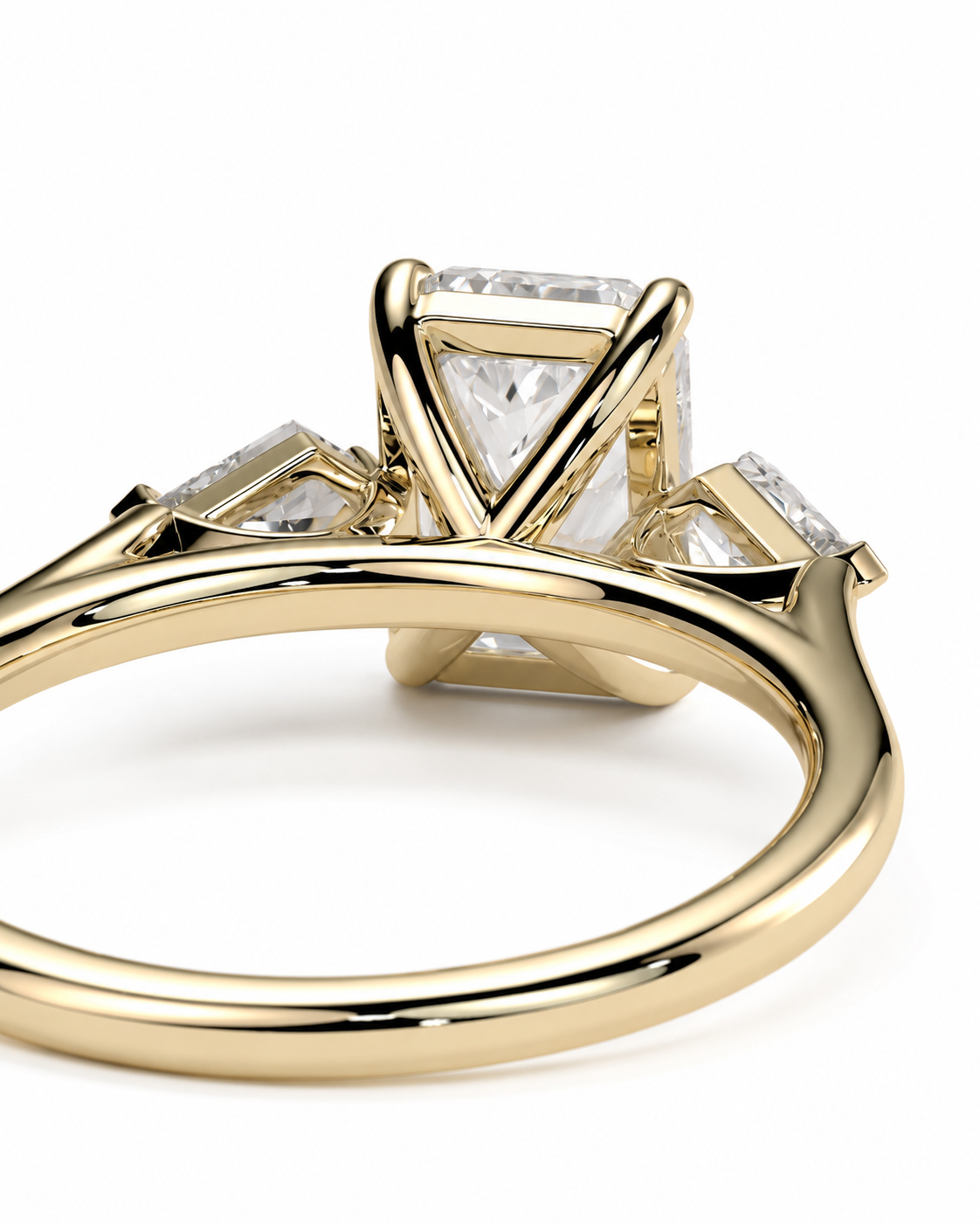 color_10K_YG, color_14K_YG &&
A close-up shot of a yellow gold ring featuring a large central rectangular diamond and two smaller diamonds on either side, set in a geometric prong design on a white background.