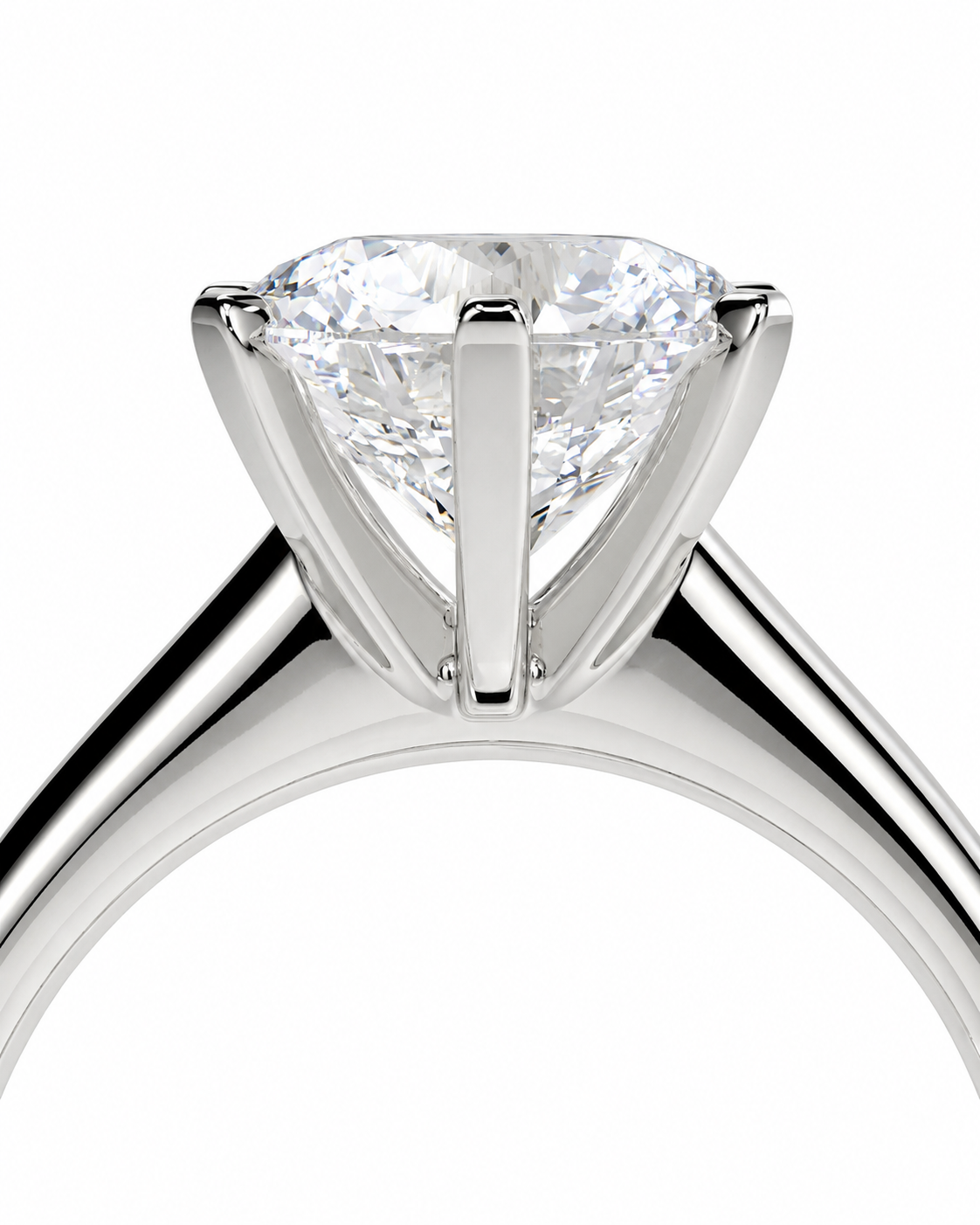color_925_SIL,color_935_ARG,color_10K_WG, color_14K_WG &&A close-up studio shot of a solitaire engagement ring featuring a round brilliant-cut diamond set in a polished silver-colored metal band, shown against a solid white background.