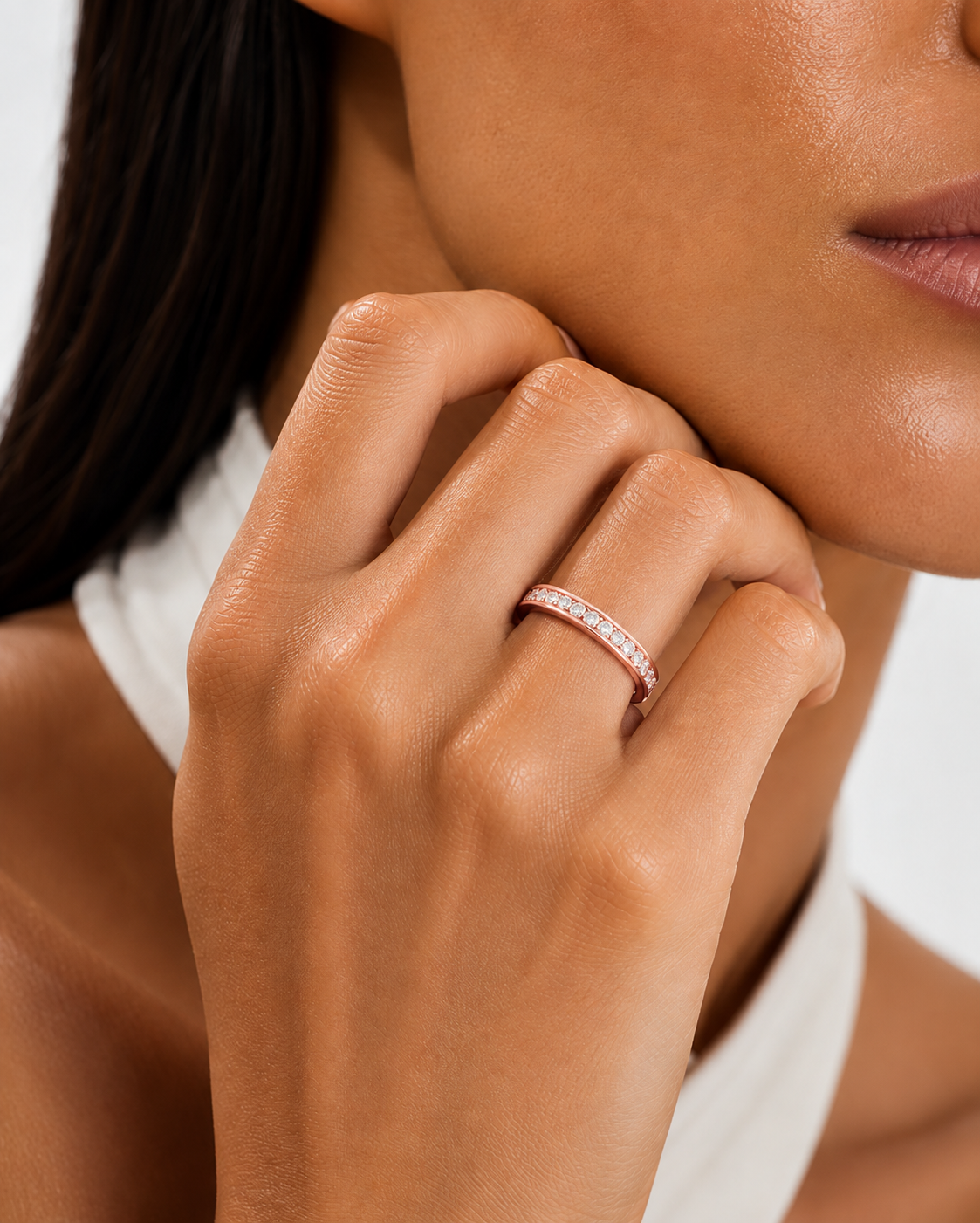 color_10K_RG, color_14K_RG &&	
A close-up lifestyle shot of a model wearing a thin rose gold band ring set with small clear stones on her finger.