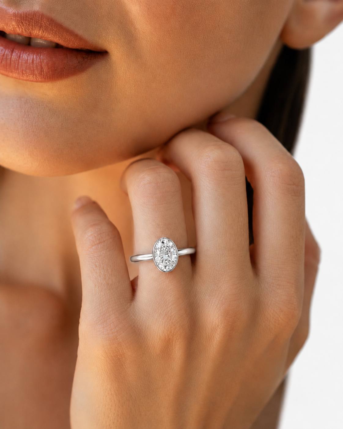 color_925_SIL,color_935_ARG,color_10K_WG, color_14K_WG &&A close-up lifestyle shot of a model wearing a silver oval diamond engagement ring on her finger.