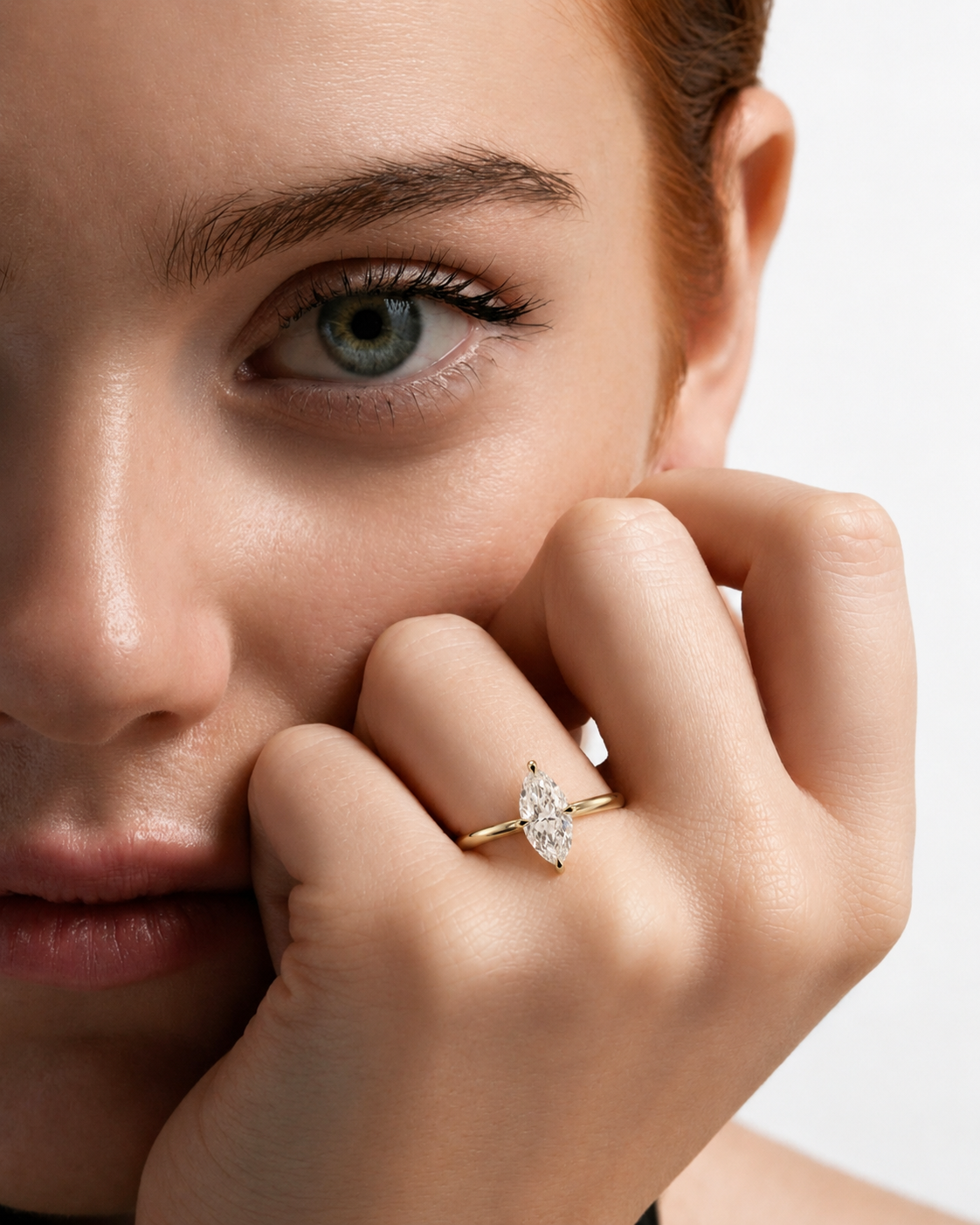 color_10K_YG, color_14K_YG &&A close-up lifestyle shot of a model wearing a delicate yellow gold ring with a marquise-cut clear gemstone on her finger, set against a clean white background.