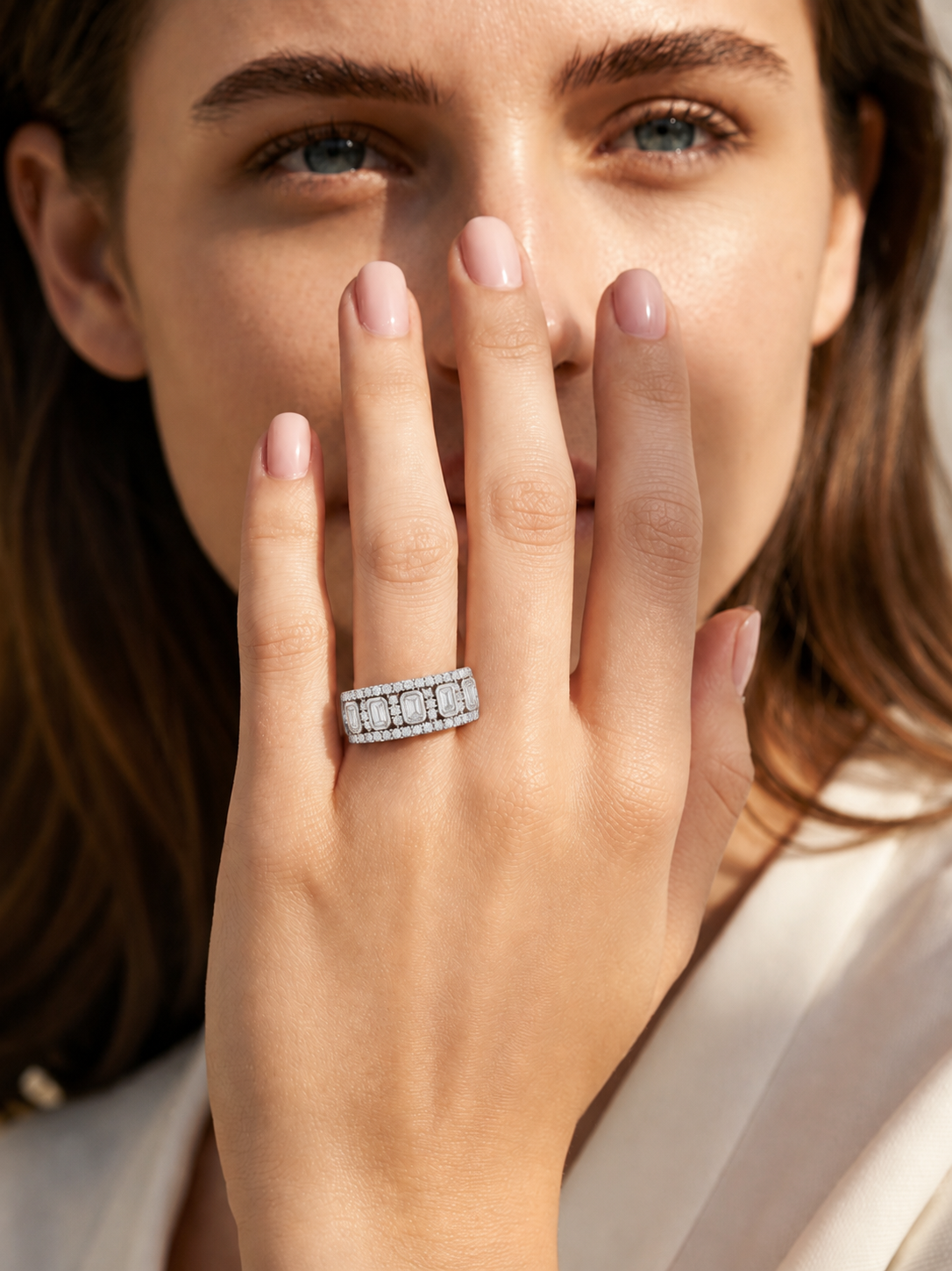 color_925_SIL,color_935_ARG,color_10K_WG, color_14K_WG &&	
A close-up lifestyle shot of a woman wearing a silver ring with rectangular baguette-cut clear gemstones on her finger, with her hand covering part of her face.