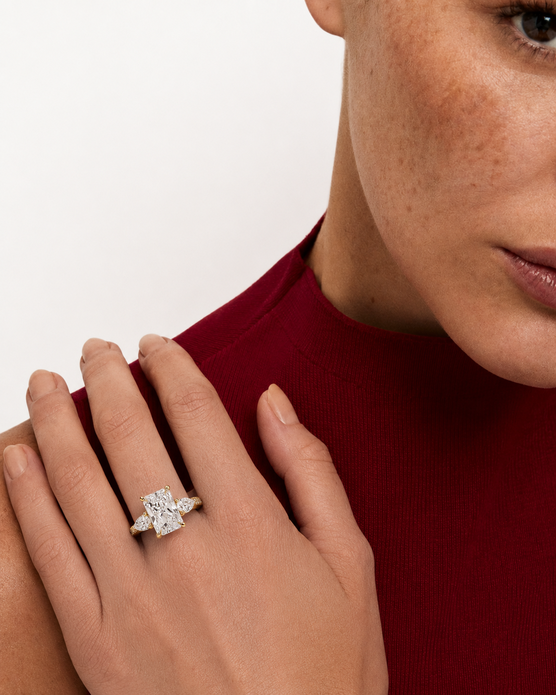 color_10K_YG, color_14K_YG &&A close-up lifestyle shot of a model wearing a silver-toned ring with a large rectangular baguette-cut center stone and smaller side stones on her hand, set against a clean white background.