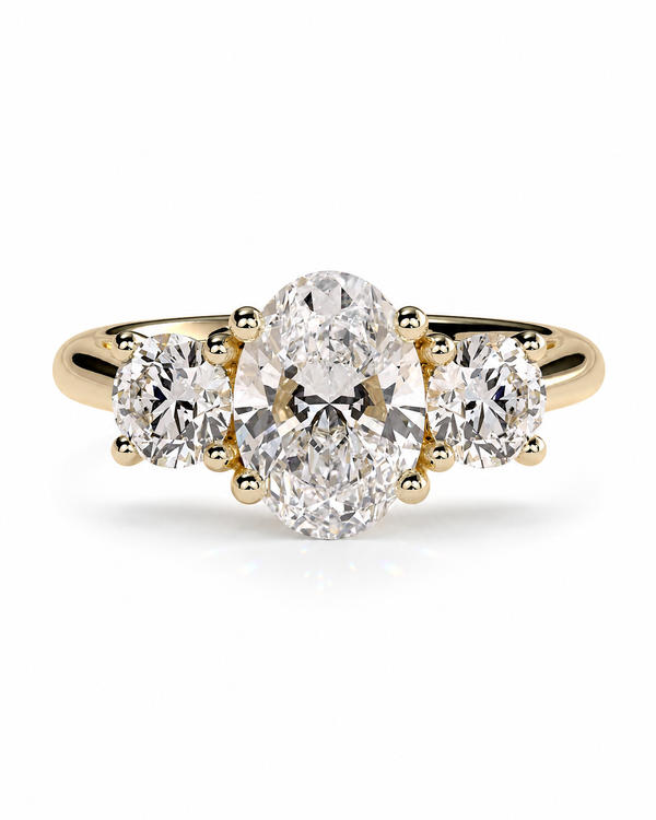 color_10K_YG, color_14K_YG &&A yellow gold three-stone diamond ring featuring a large oval center diamond flanked by two round side diamonds, set against a clean white background.