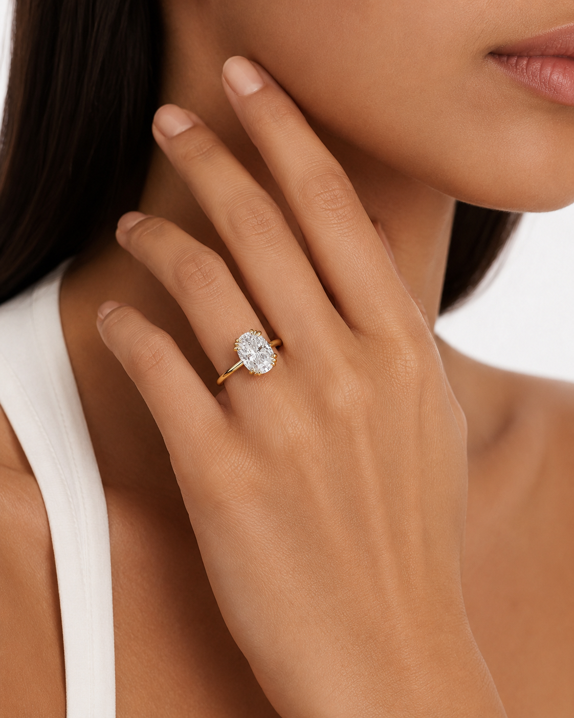 color_10K_YG, color_14K_YG &&A close-up lifestyle shot of a model wearing a yellow gold ring with an oval-cut clear gemstone on her finger.