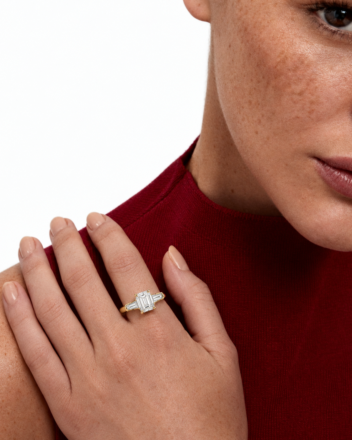 color_10K_YG, color_14K_YG &&A close-up of a woman's hand wearing a gold ring with a rectangular baguette-cut clear center stone and smaller side stones, set against a white background.