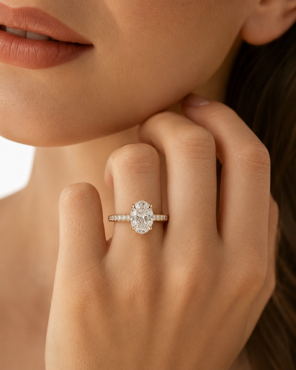color_10K_YG, color_14K_YG &&A close-up lifestyle shot of a model wearing a silver-toned ring with a large oval-cut clear center stone and small side stones.