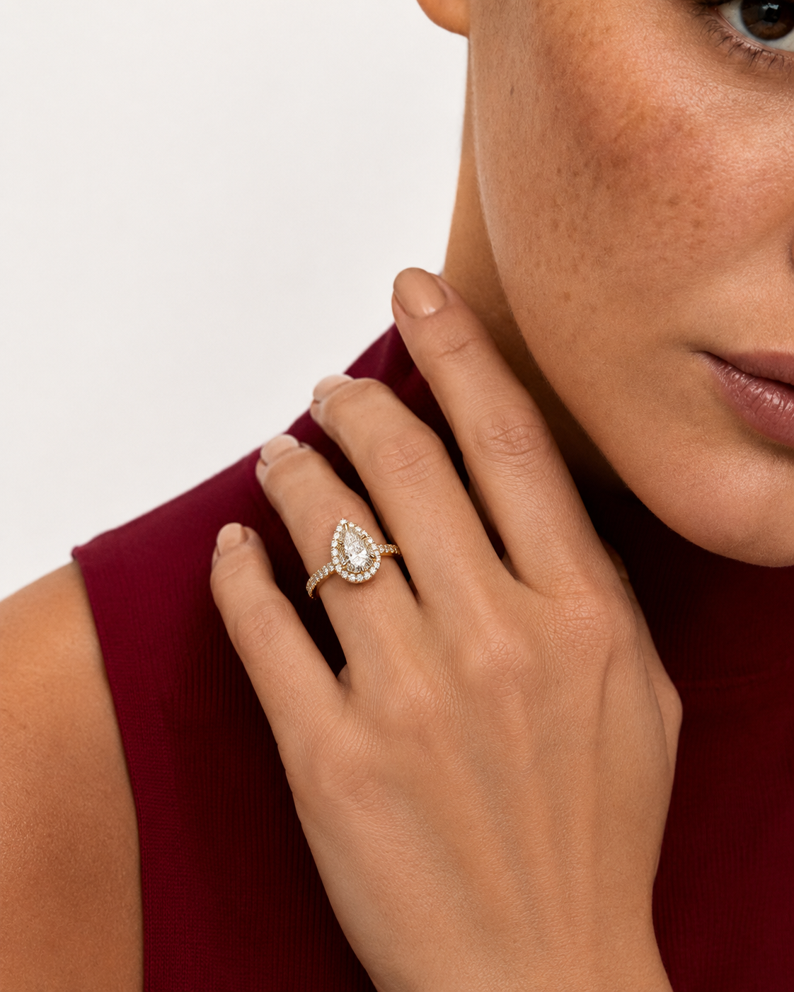 color_10K_YG, color_14K_YG &&A close-up lifestyle shot of a model wearing a gold ring with a pear-cut clear gemstone and small surrounding stones, set against a clean white background.