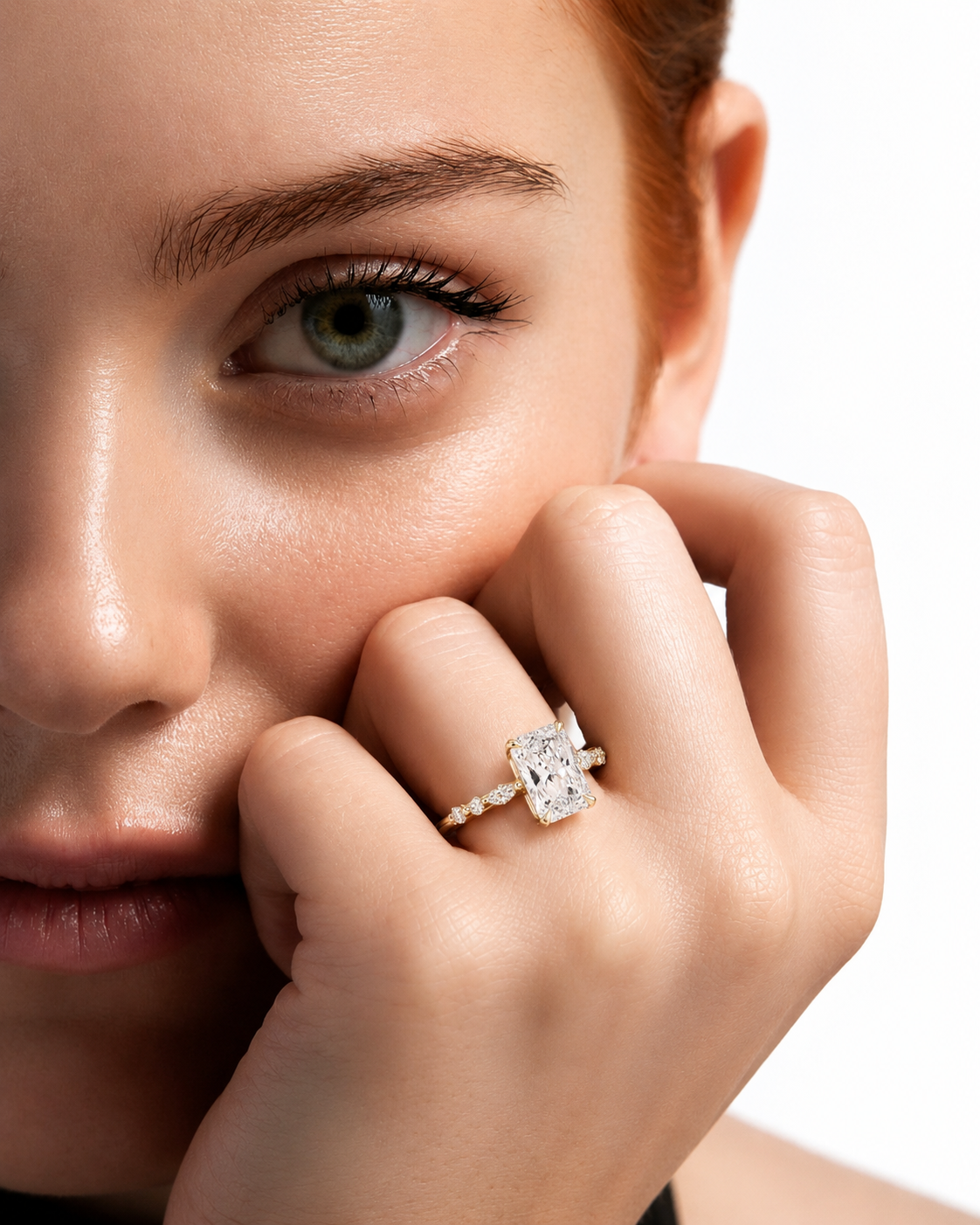 color_10K_YG, color_14K_YG &&A close-up lifestyle shot of a model wearing a diamond engagement ring on her finger, with her hand resting near her cheek against a clean white background.