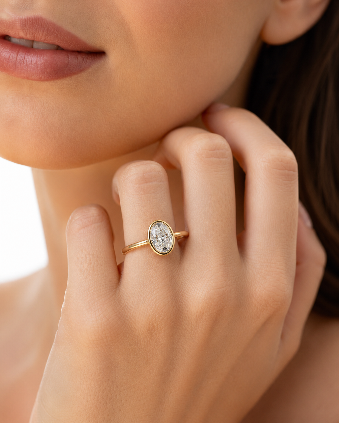 color_10K_YG, color_14K_YG &&close-up lifestyle shot of a model wearing a delicate gold ring with a bezel-set clear marquise-cut gemstone on her finger.