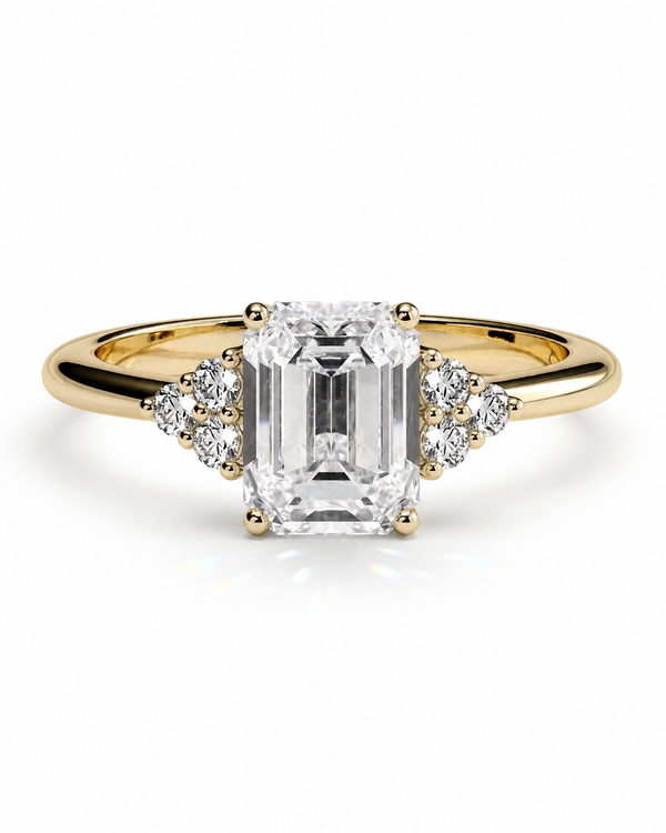 color_10K_YG, color_14K_YG &&A yellow gold engagement ring featuring a large emerald-cut center diamond flanked by small round diamonds on the band, set against a clean white background.