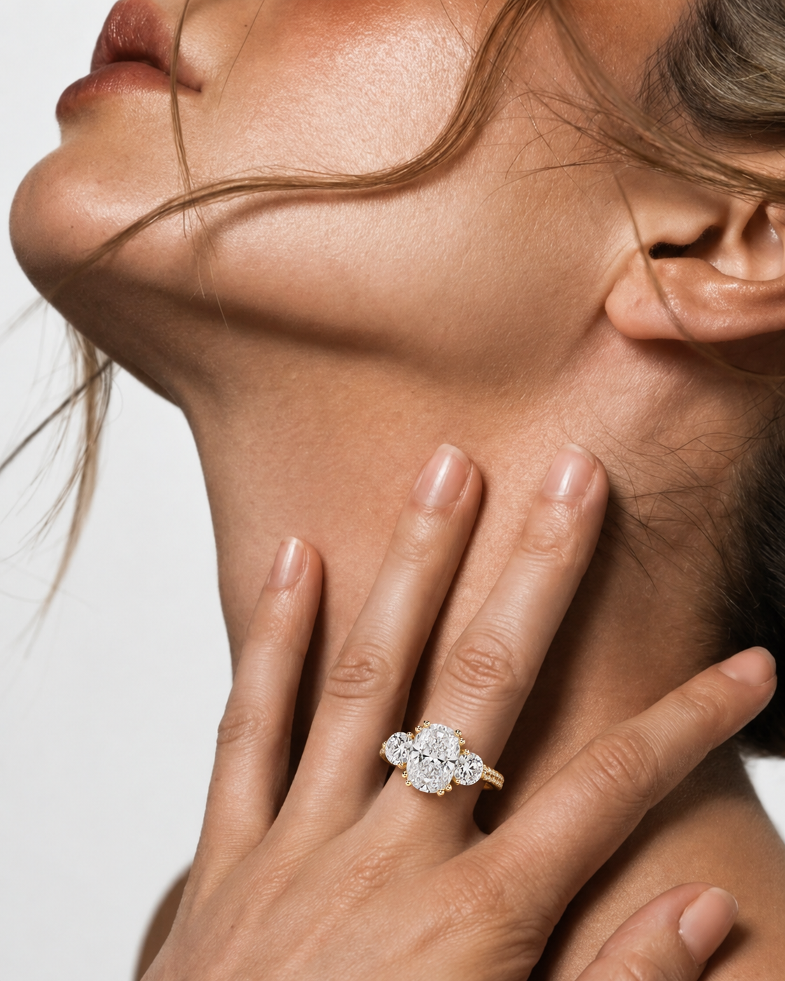 color_10K_YG, color_14K_YG &&A close-up lifestyle shot of a model wearing a diamond ring with a gold band. The model's hand and neck are visible against a clean, light gray background.