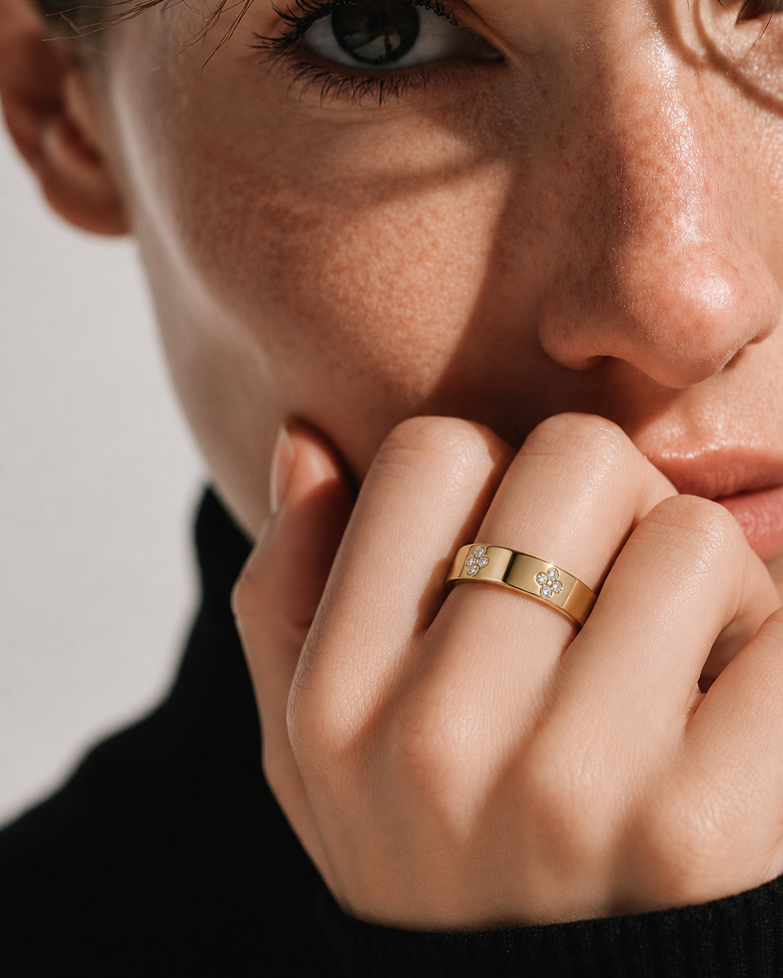 color_10K_YG, color_14K_YG &&A close-up lifestyle shot of a model wearing a gold band ring with small clear stones on the side, resting her chin on her hand against a neutral light background.