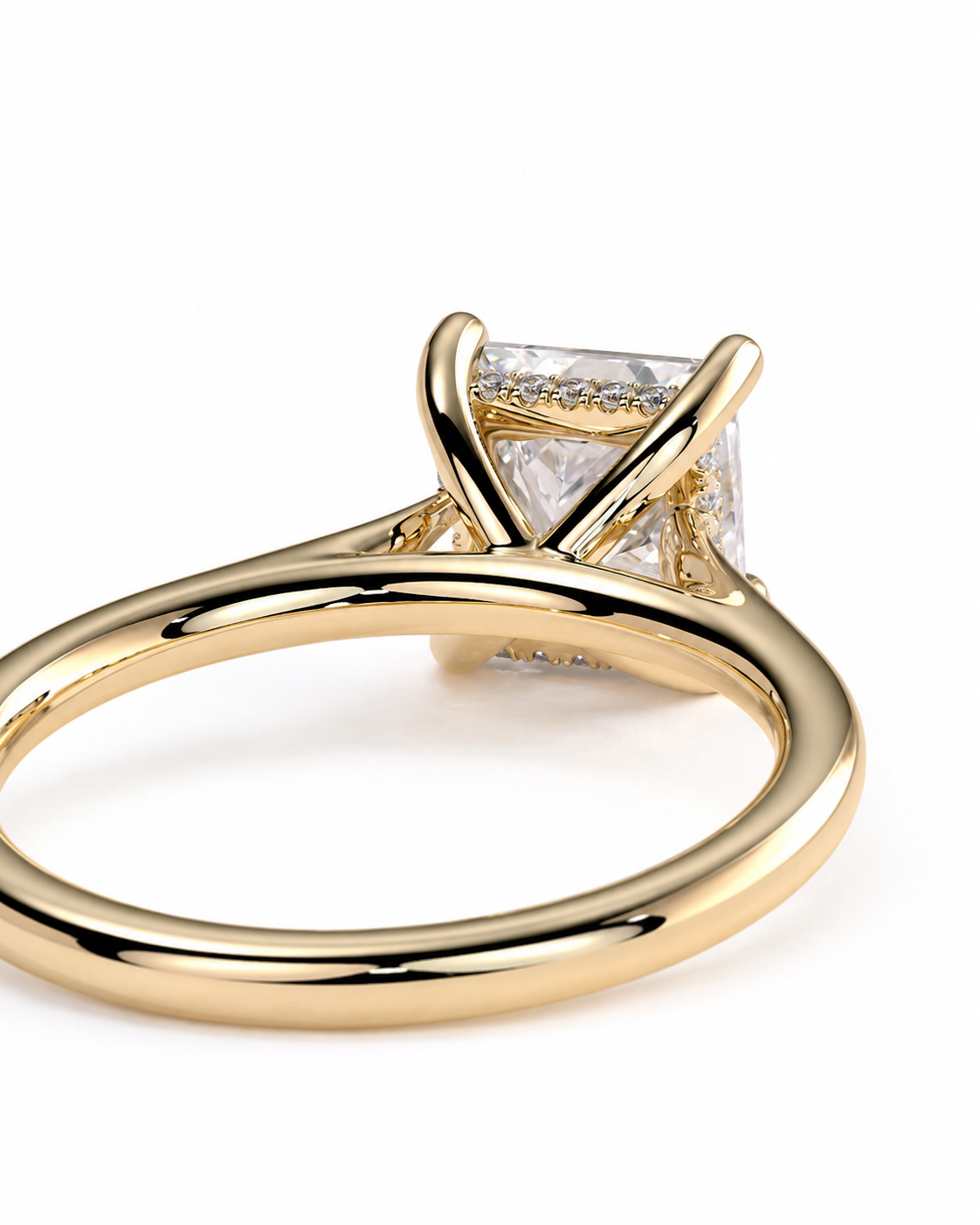 color_10K_YG, color_14K_YG &&A close-up shot of a yellow gold ring featuring a square princess-cut clear gemstone in a four-prong setting, with a shank decorated with small round diamonds, on a white background.
