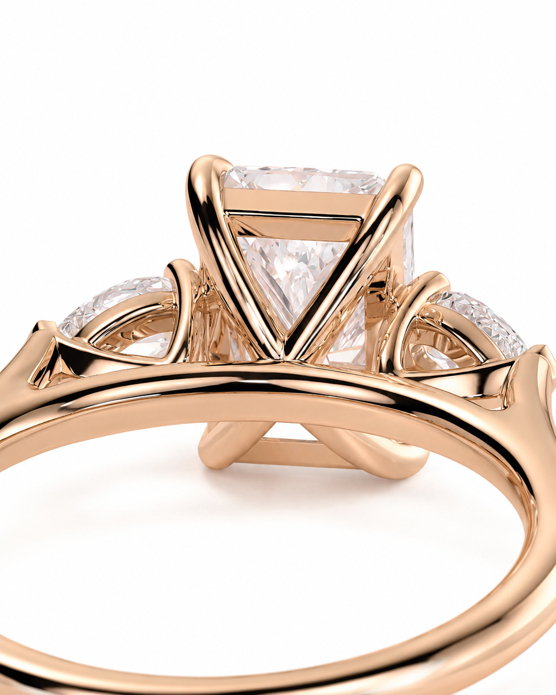 color_10K_RG, color_14K_RG &&
A close-up of a rose gold ring featuring a large rectangular clear gemstone in a triangular prong setting, with smaller accent stones along the band, shown on a white background.