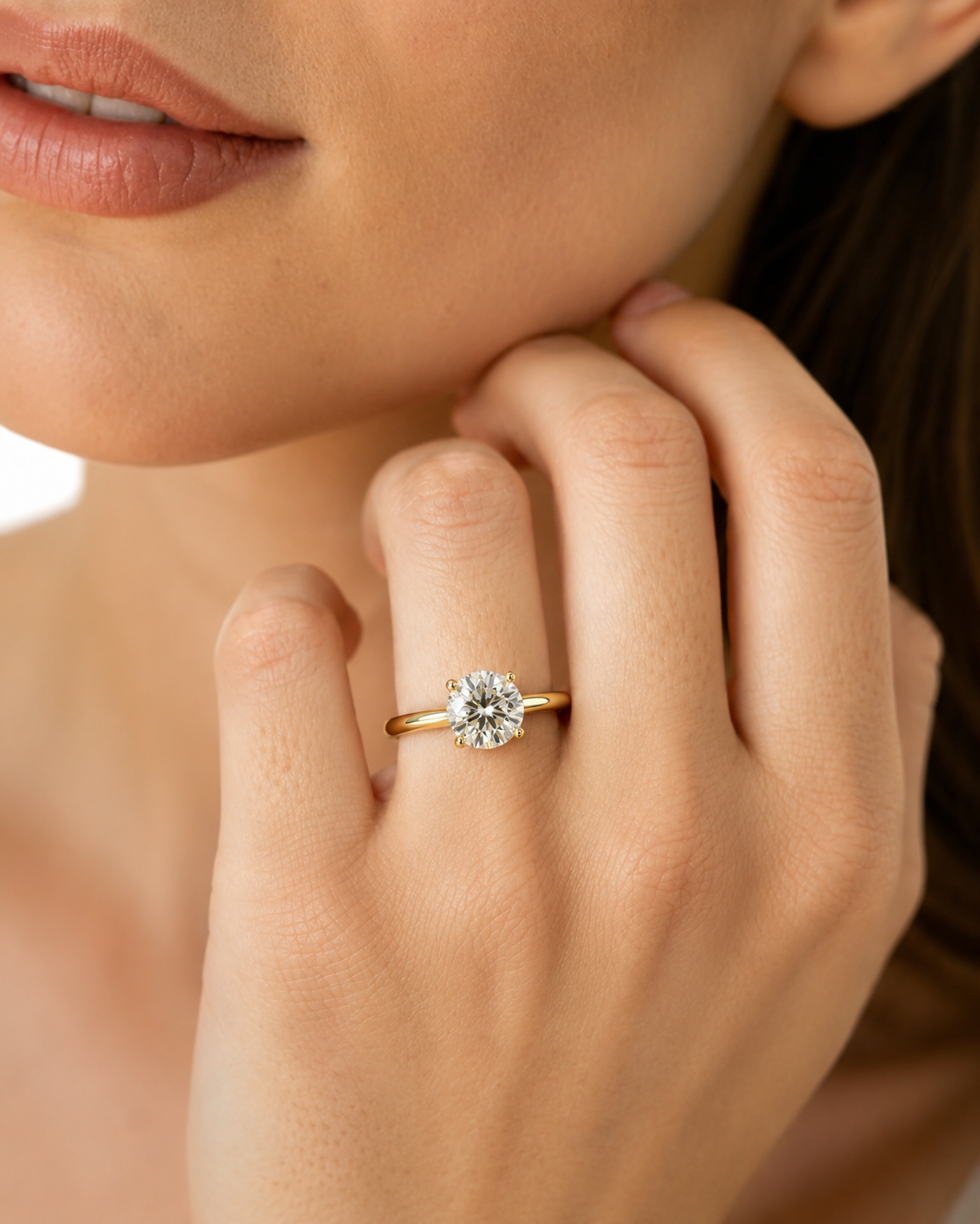 color_10K_YG, color_14K_YG &&	
A close-up lifestyle shot of a woman wearing a yellow gold engagement ring with a round brilliant-cut diamond on her finger.