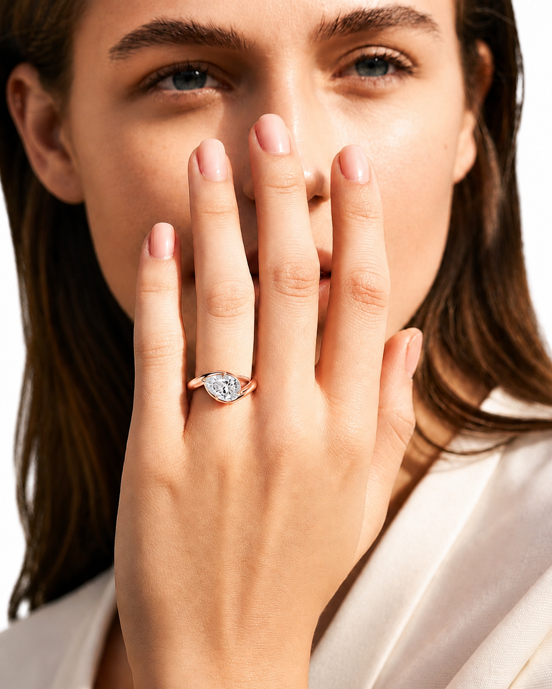 color_10K_RG, color_14K_RG &&
A close-up lifestyle shot of a woman wearing a heart-shaped diamond ring on her finger, with her hand covering part of her face against a clean white background.