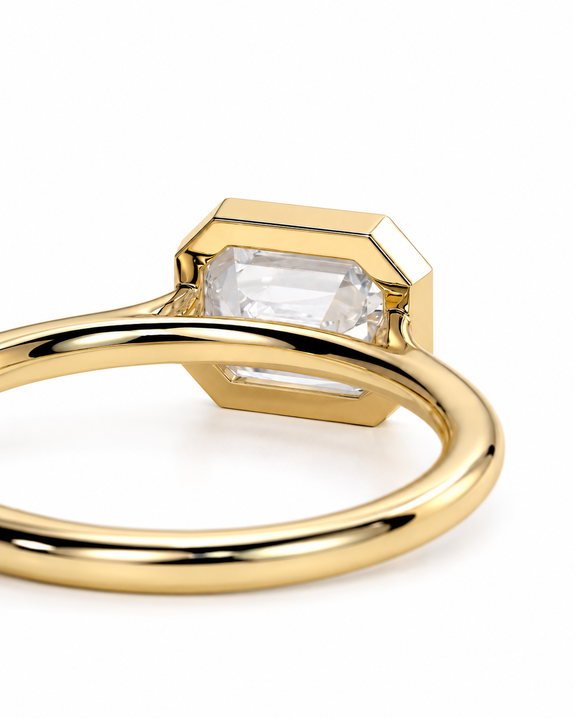 color_10K_YG, color_14K_YG &&	
A close-up shot of a gold ring featuring a geometric, faceted bezel setting with a clear rectangular emerald-cut gemstone, set against a plain white background.