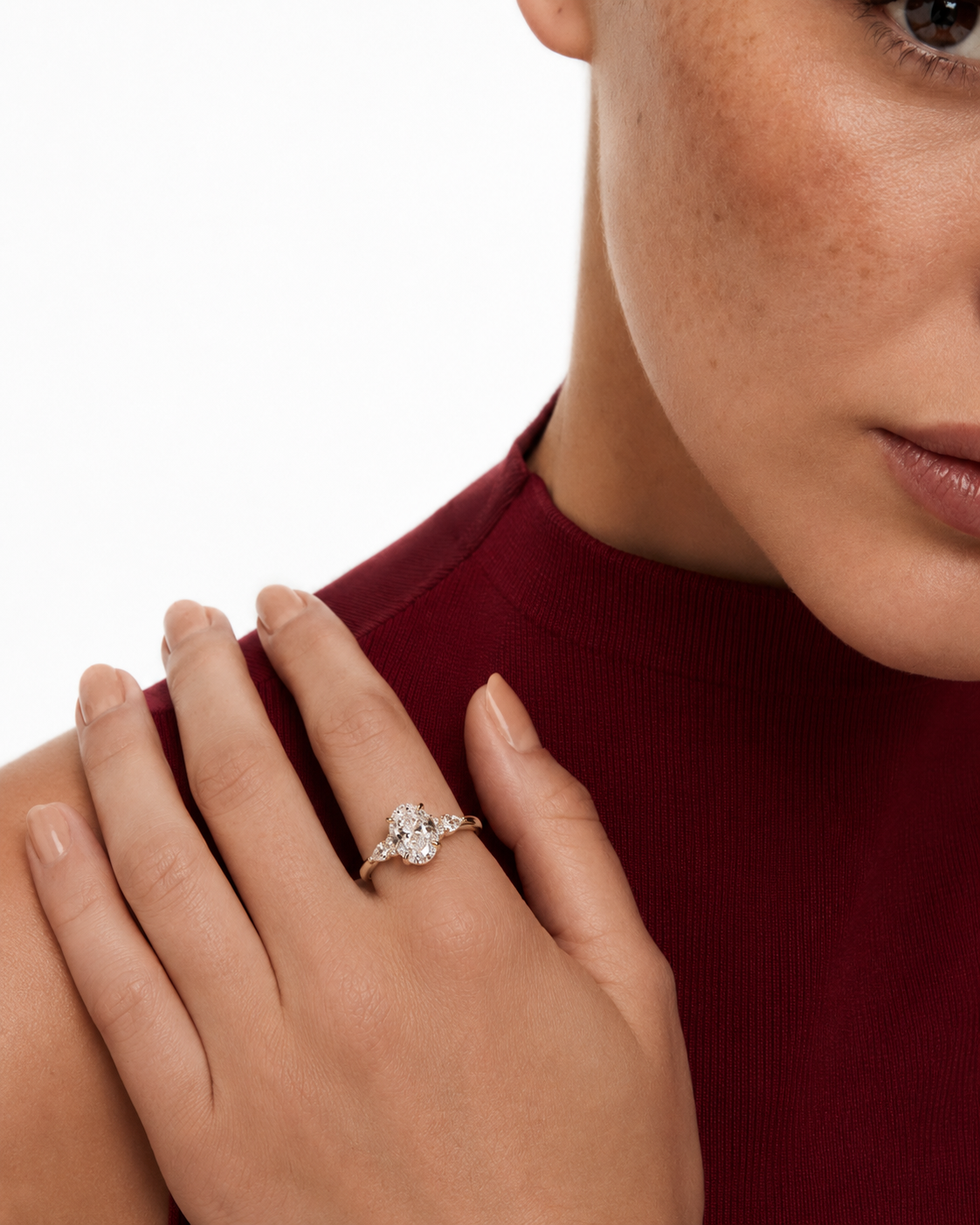 color_10K_YG, color_14K_YG &&A close-up lifestyle shot of a woman wearing a diamond ring on her finger, dressed in a deep burgundy ribbed top against a clean white background.