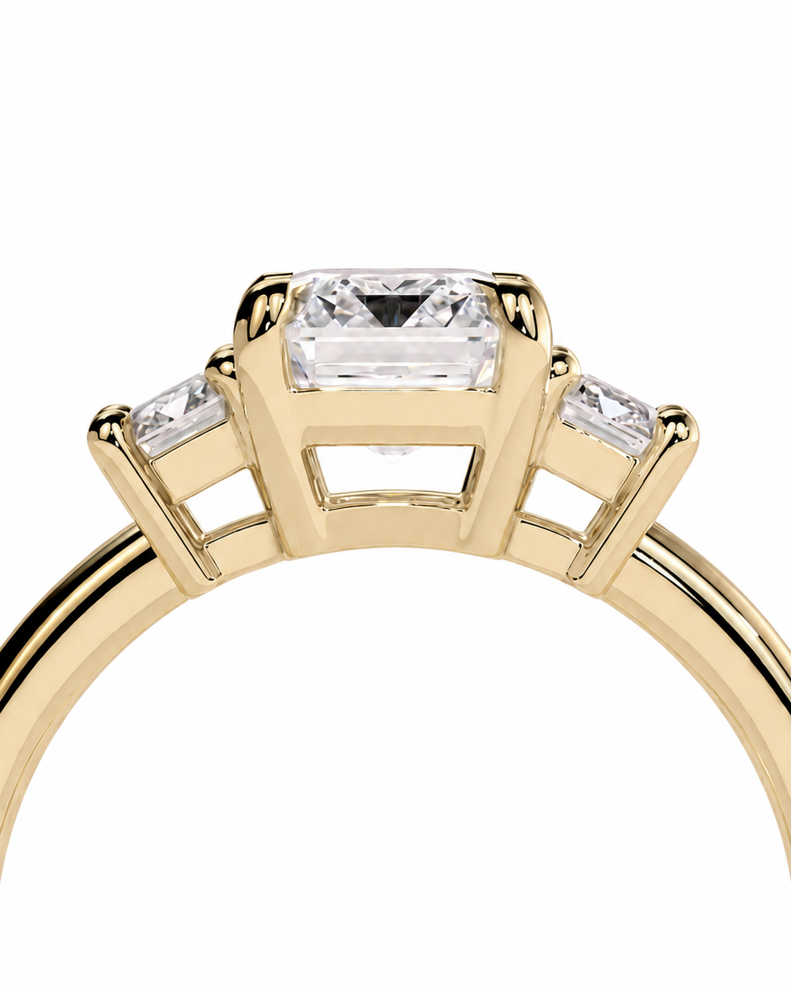 color_10K_YG, color_14K_YG &&A close-up of a yellow gold ring featuring a rectangular emerald-cut center stone and two smaller round-cut side stones, set against a plain white background.