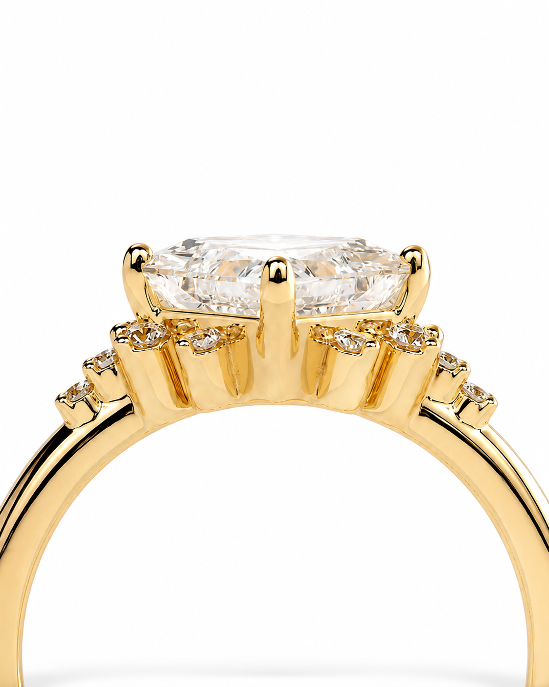 color_10K_YG, color_14K_YG &&A close-up of a yellow gold ring featuring a large cushion-cut clear center stone and smaller accent stones along the shoulders, set against a plain white background.
