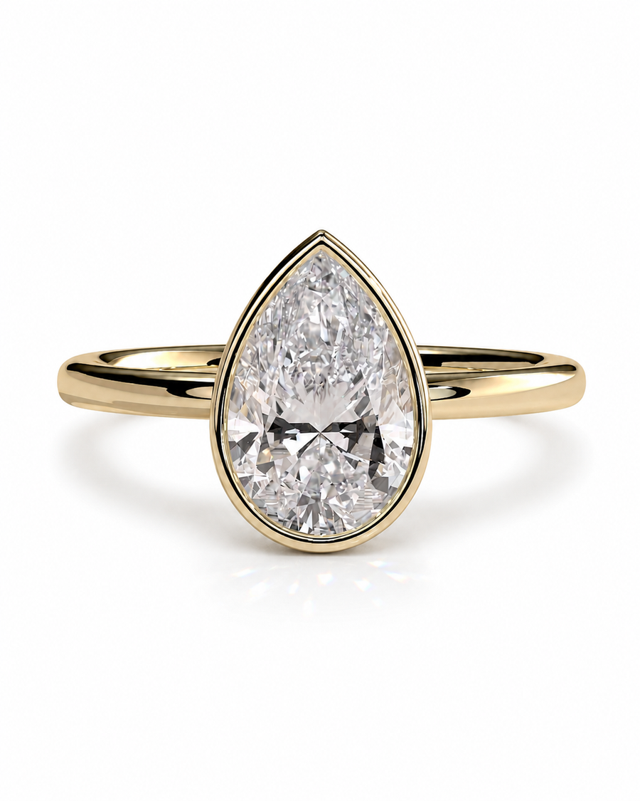 color_10K_YG, color_14K_YG &&A pear-cut diamond engagement ring in a yellow gold band, shown on a clean white background with a soft reflection.