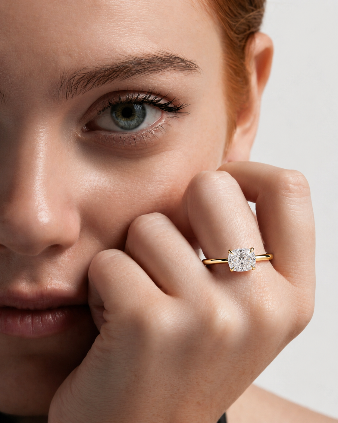 color_10K_YG, color_14K_YG &&A close-up lifestyle shot of a model wearing a gold ring with a round-cut clear gemstone on her finger, set against a clean light gray background.