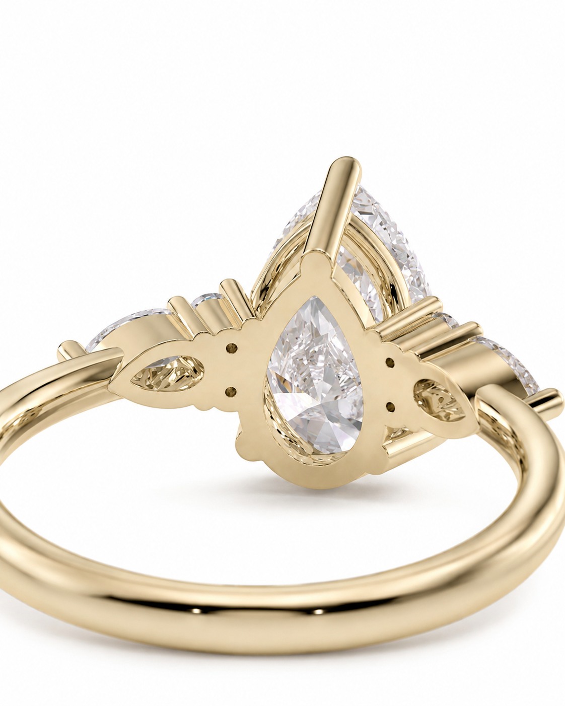 color_10K_YG, color_14K_YG &&A close-up shot of a gold ring featuring a pear-cut clear center stone and smaller side stones, set against a plain white background.