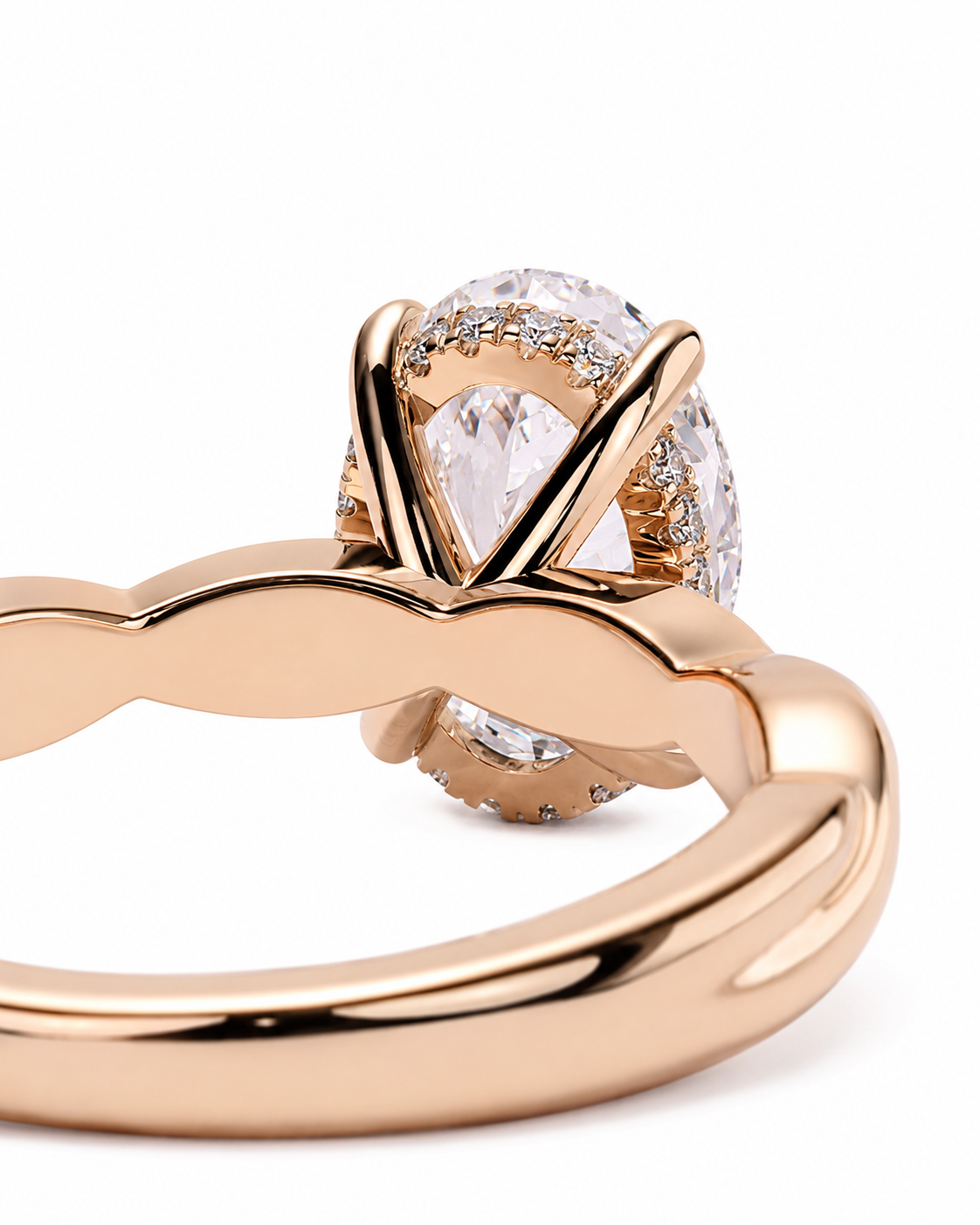 color_10K_RG, color_14K_RG &&
A close-up of a rose gold ring featuring a pear-cut clear center stone surrounded by a halo of small clear stones, set on a polished twisted band.