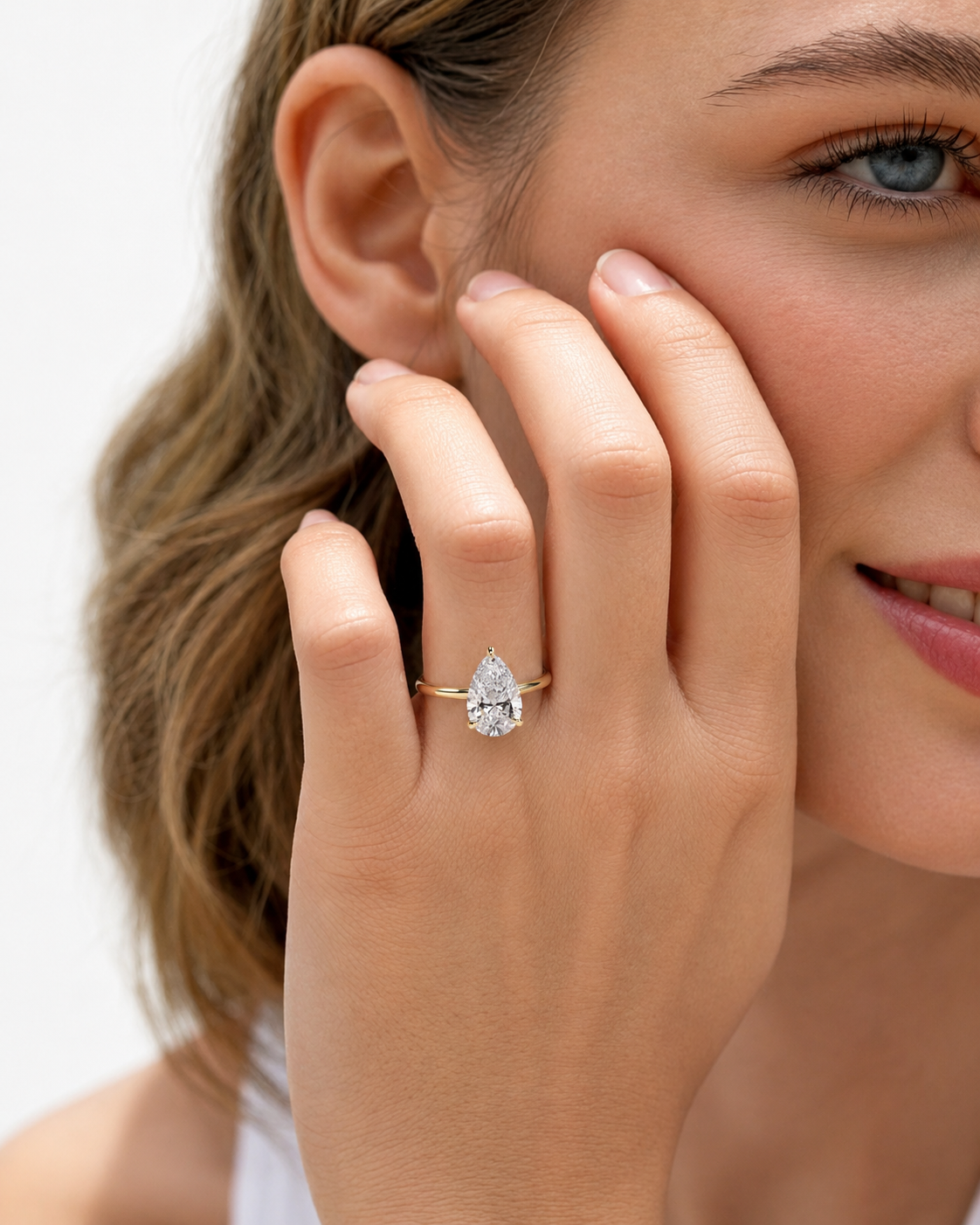 color_10K_YG, color_14K_YG &&A close-up lifestyle shot of a woman wearing a rose gold engagement ring with a round-cut clear gemstone on her finger, with her hand resting against her cheek against a white background.