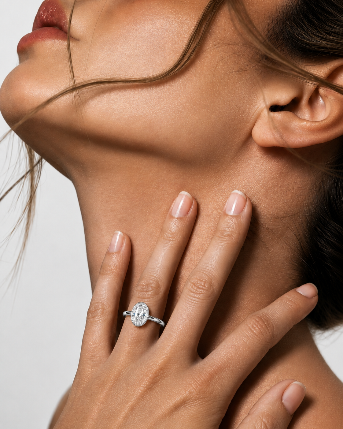 color_925_SIL,color_935_ARG,color_10K_WG, color_14K_WG &&
A close-up lifestyle shot of a woman's hand and neck, wearing a silver-toned oval ring with a clear central gemstone.