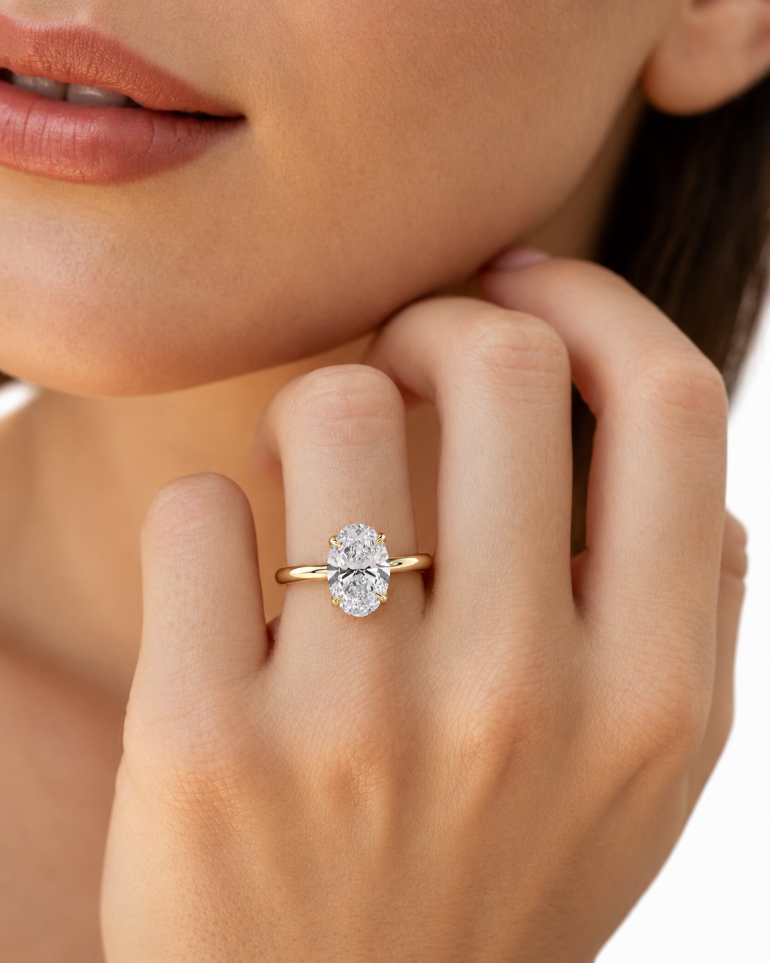 color_10K_YG, color_14K_YG &&A close-up lifestyle shot of a model wearing a yellow gold ring with a large oval-cut clear gemstone on her finger.