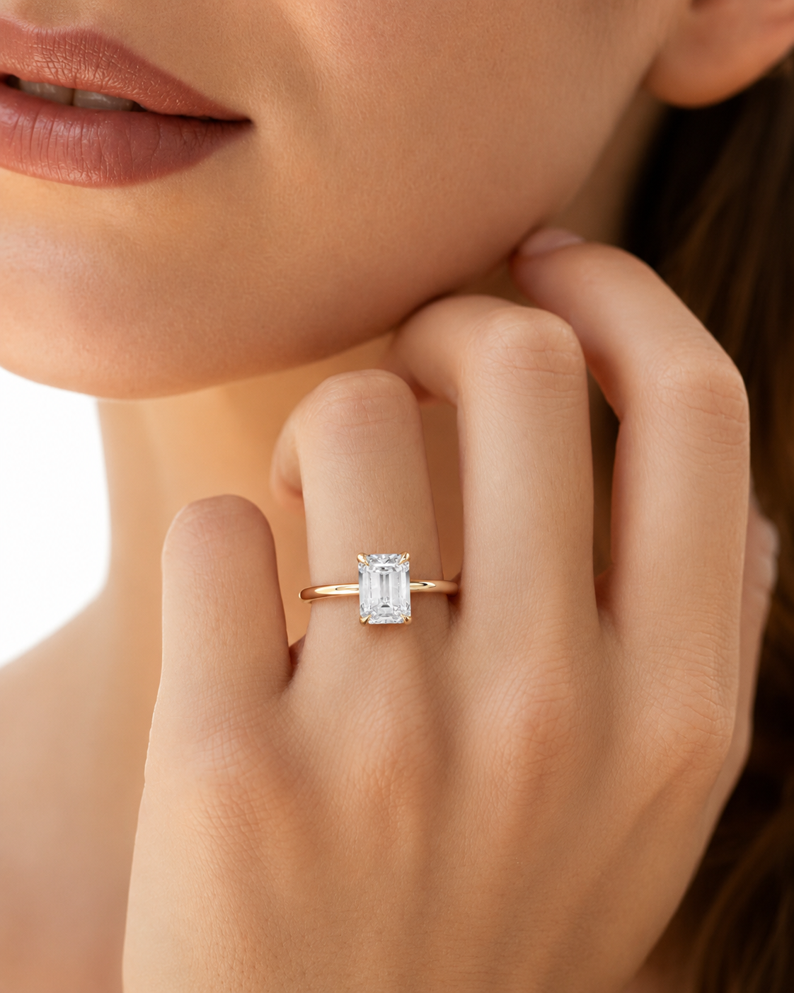 color_10K_YG, color_14K_YG &&A close-up lifestyle shot of a model's hand wearing a gold ring with a rectangular emerald-cut clear gemstone.