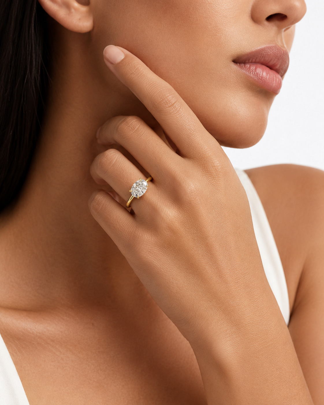 color_10K_YG, color_14K_YG &&A close-up lifestyle shot of a model wearing a yellow gold ring with a marquise-cut diamond. The ring is shown on her finger, with her hand resting near her face against a clean white background.