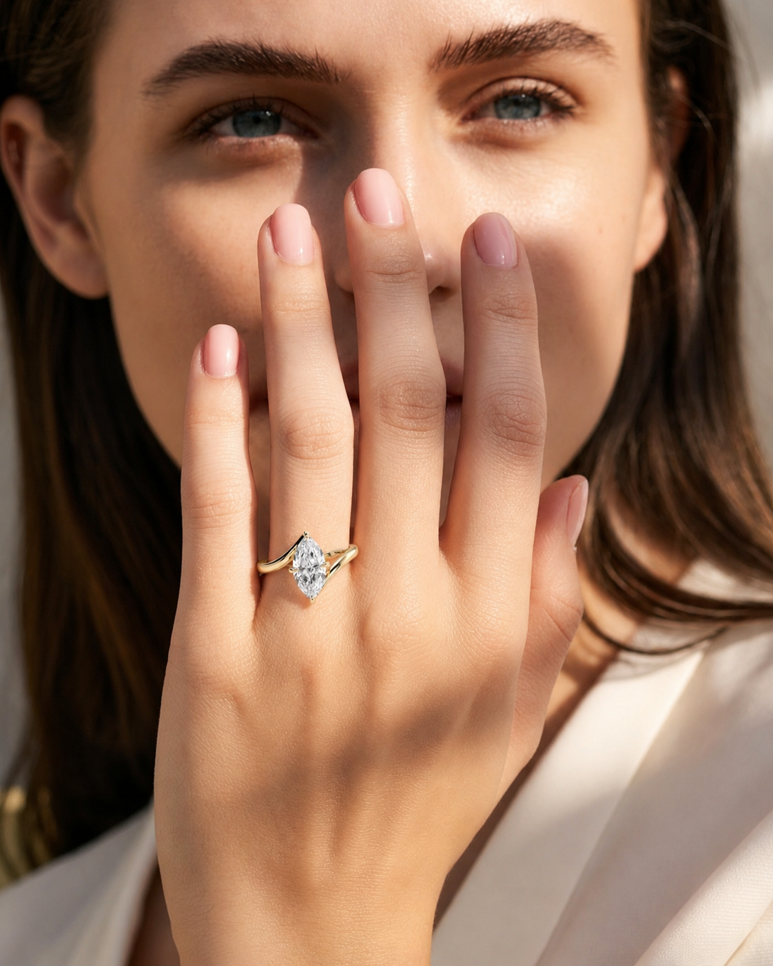color_10K_YG, color_14K_YG &&
A close-up lifestyle shot of a woman wearing a diamond ring with a gold band. The ring features a marquise-cut diamond set in a diamond-shaped gold halo with curved gold accents on the band.