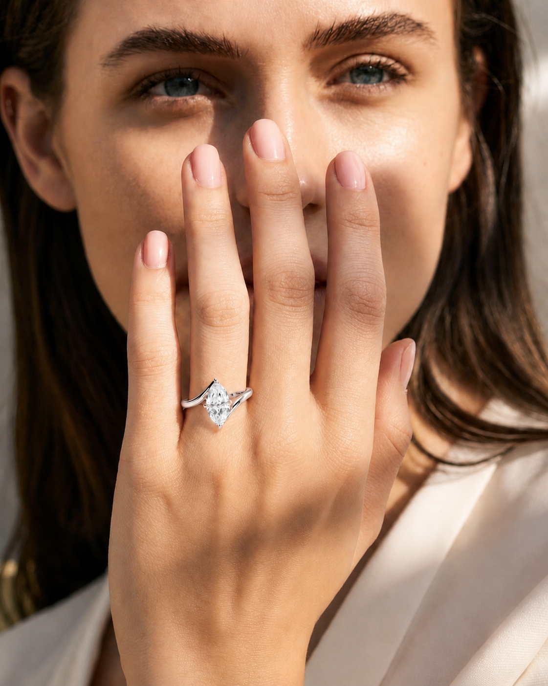 color_925_SIL,color_935_ARG,color_10K_WG, color_14K_WG &&
A close-up lifestyle shot of a woman wearing a silver ring with a clear marquise-cut gemstone, holding her hand near her face.