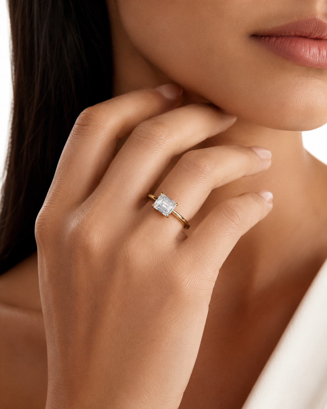 color_10K_YG, color_14K_YG &&A close-up lifestyle shot of a woman wearing a gold ring with a rectangular clear gemstone on her finger.