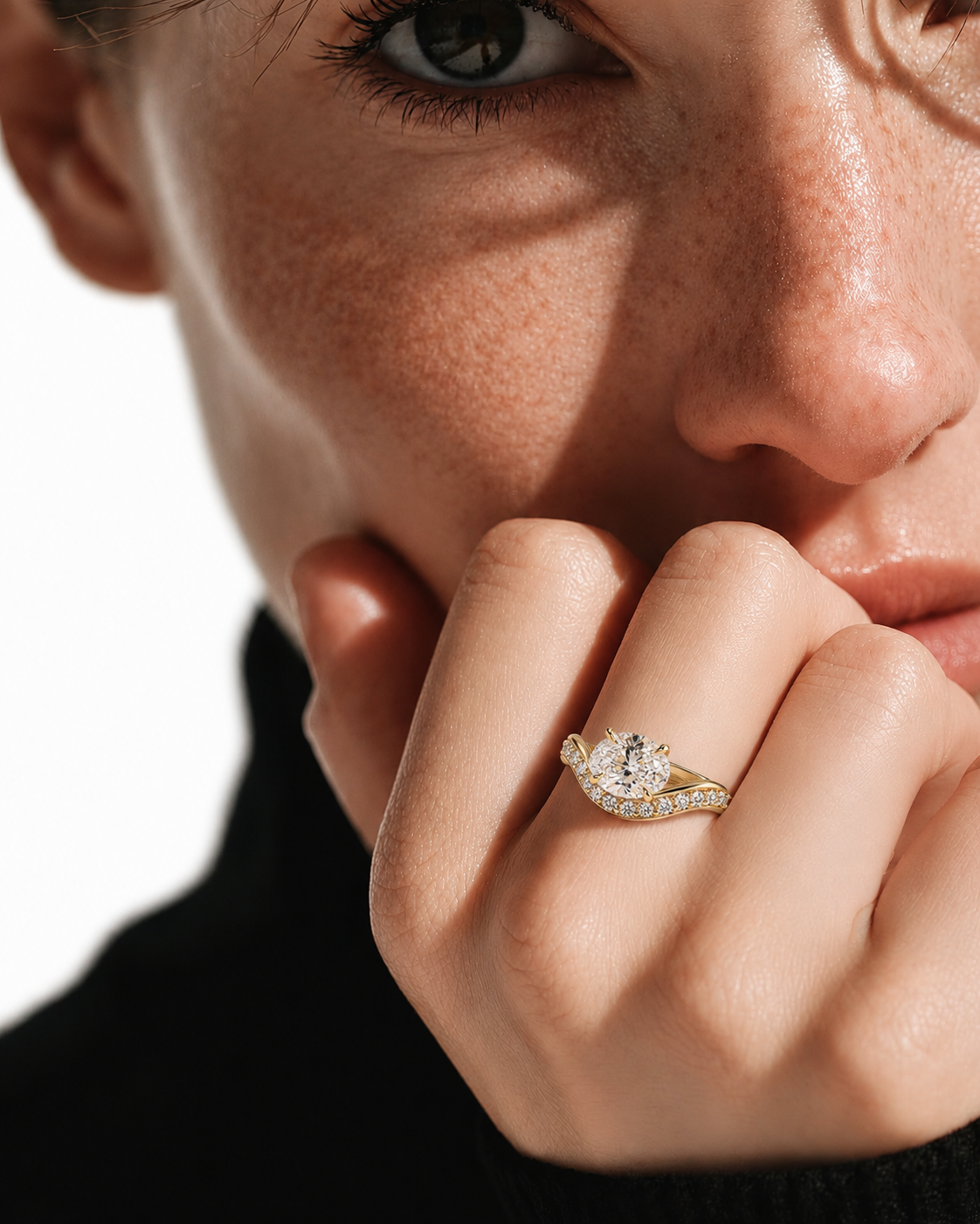 color_10K_YG, color_14K_YG &&A close-up lifestyle shot of a model wearing a yellow gold diamond ring with a halo of smaller diamonds, resting on her finger as she looks off-camera.