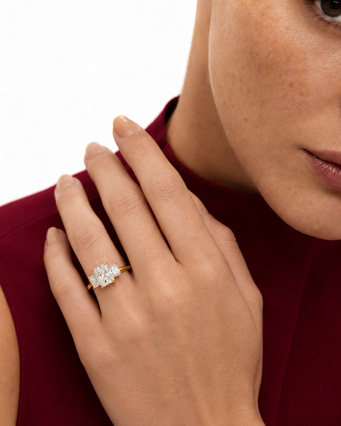 color_10K_YG, color_14K_YG &&A close-up lifestyle shot of a woman's hand wearing a diamond ring with a gold band, set against her shoulder and neck.