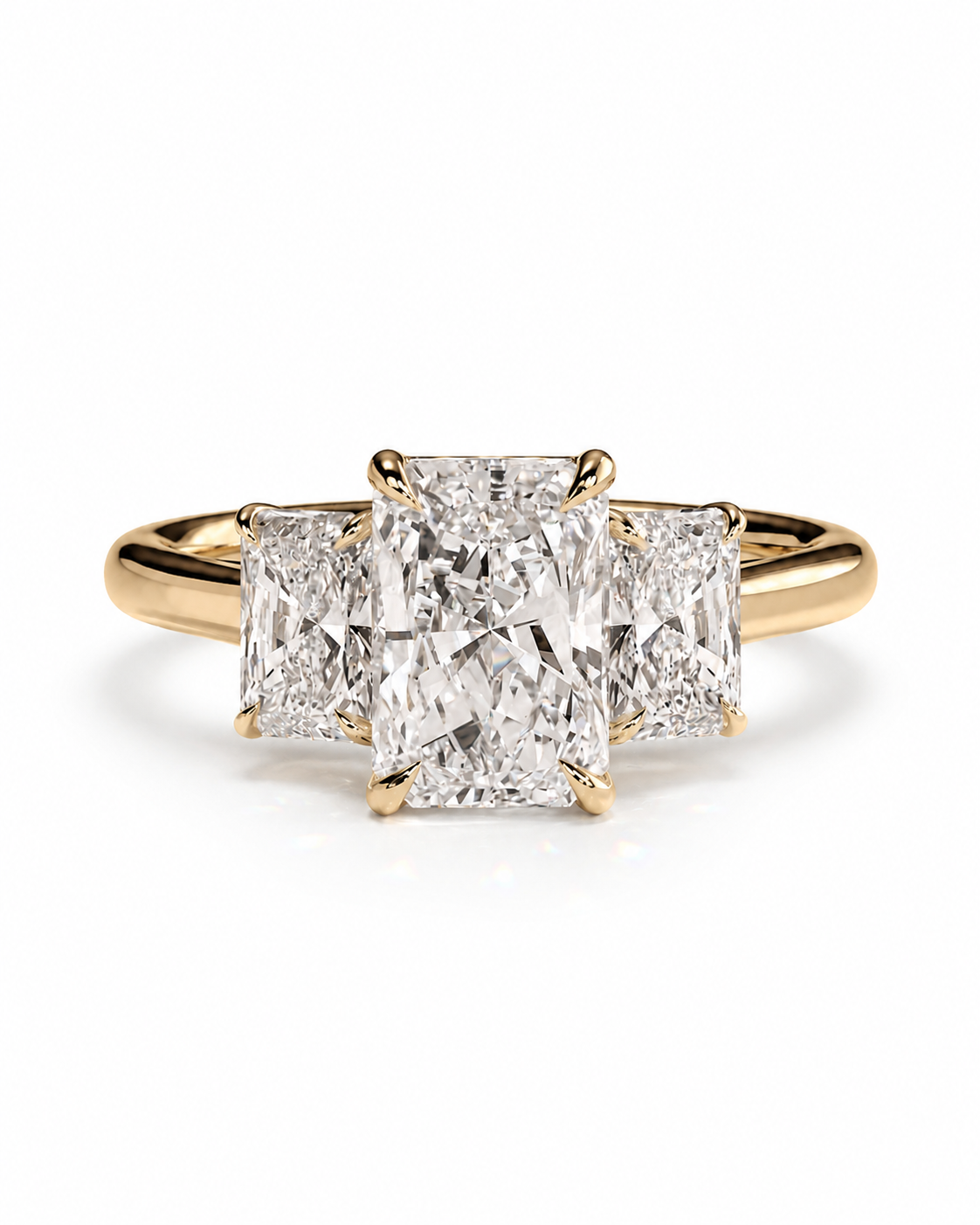 color_10K_YG, color_14K_YG &&A yellow gold three-stone ring featuring a large rectangular radiant-cut center diamond flanked by two smaller round brilliant-cut diamonds, set on a polished gold band against a clean white background.