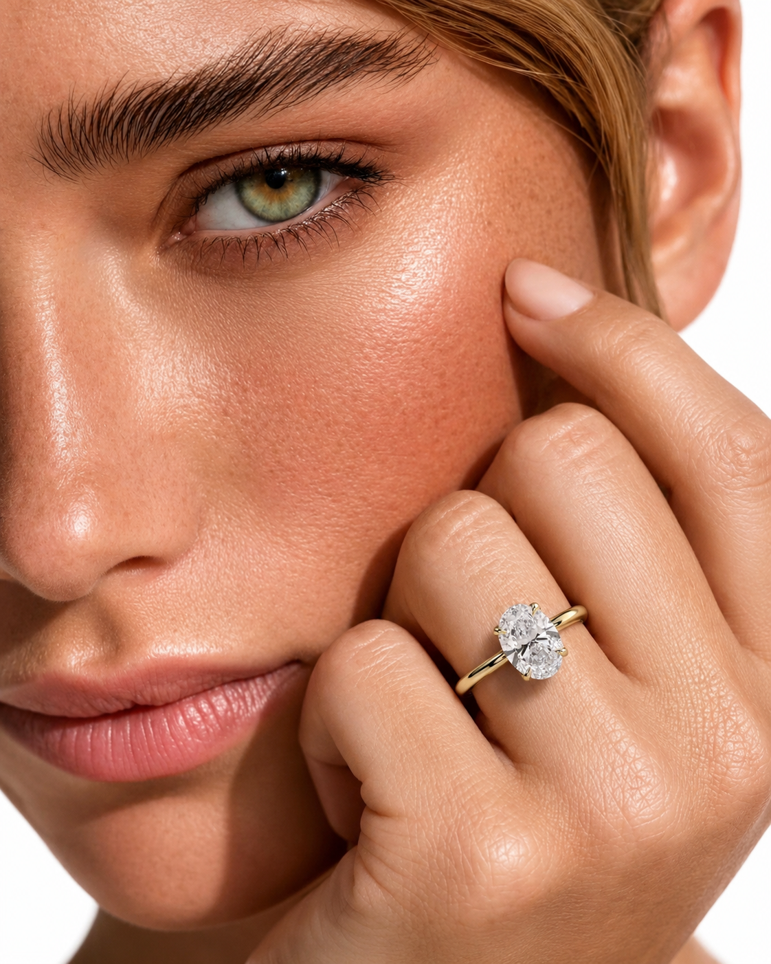 color_10K_YG, color_14K_YG &&A close-up lifestyle shot of a model wearing a yellow gold ring with a round brilliant-cut diamond. The model's face and hand are shown against a clean white background.
