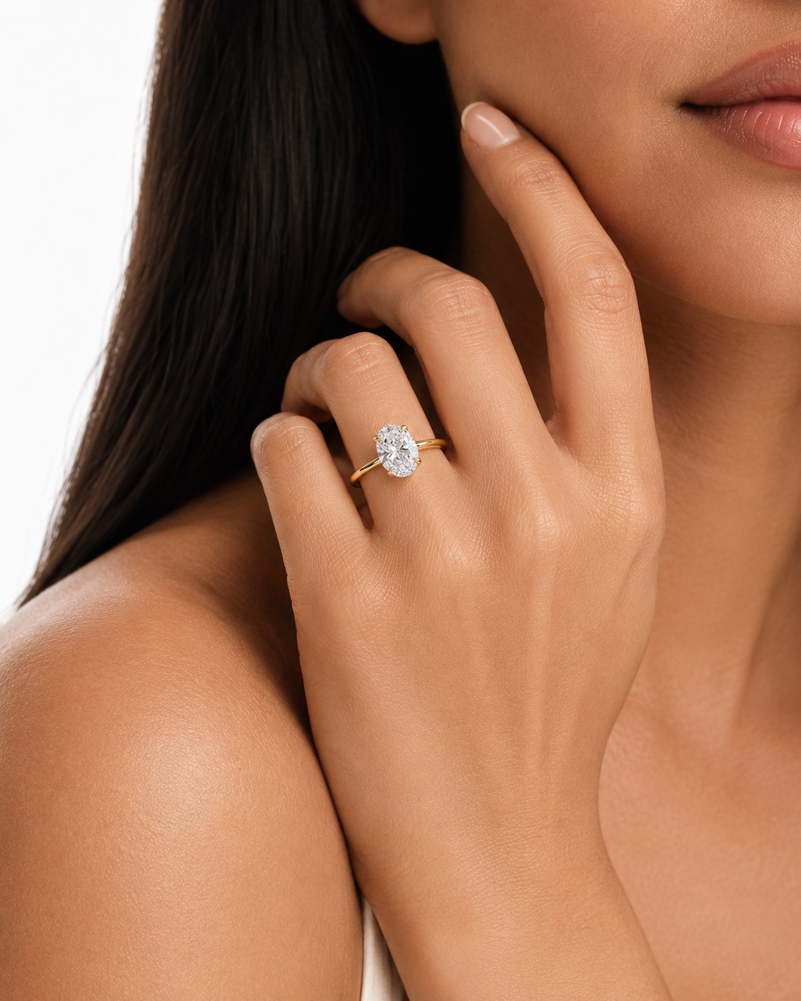 color_10K_YG, color_14K_YG &&A close-up lifestyle shot of a woman wearing a yellow gold ring with a round brilliant-cut diamond on her ring finger. The background is a clean white studio backdrop.