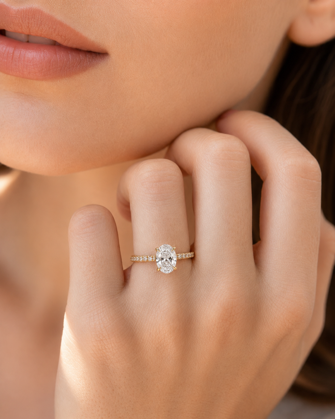 color_10K_YG, color_14K_YG &&A close-up lifestyle shot of a model's hand wearing a yellow gold ring with a round-cut clear center stone and a pavé band.
