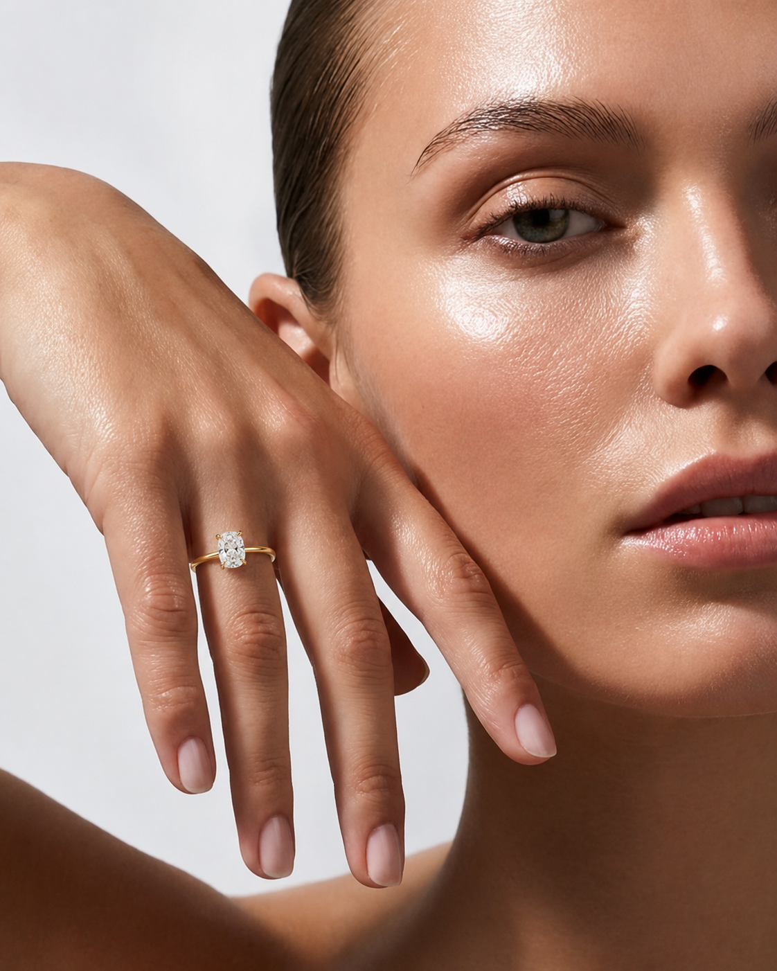 color_10K_YG, color_14K_YG &&A close-up lifestyle shot of a model wearing a delicate yellow gold ring with a round-cut clear gemstone on her finger, set against a clean, light gray background.
