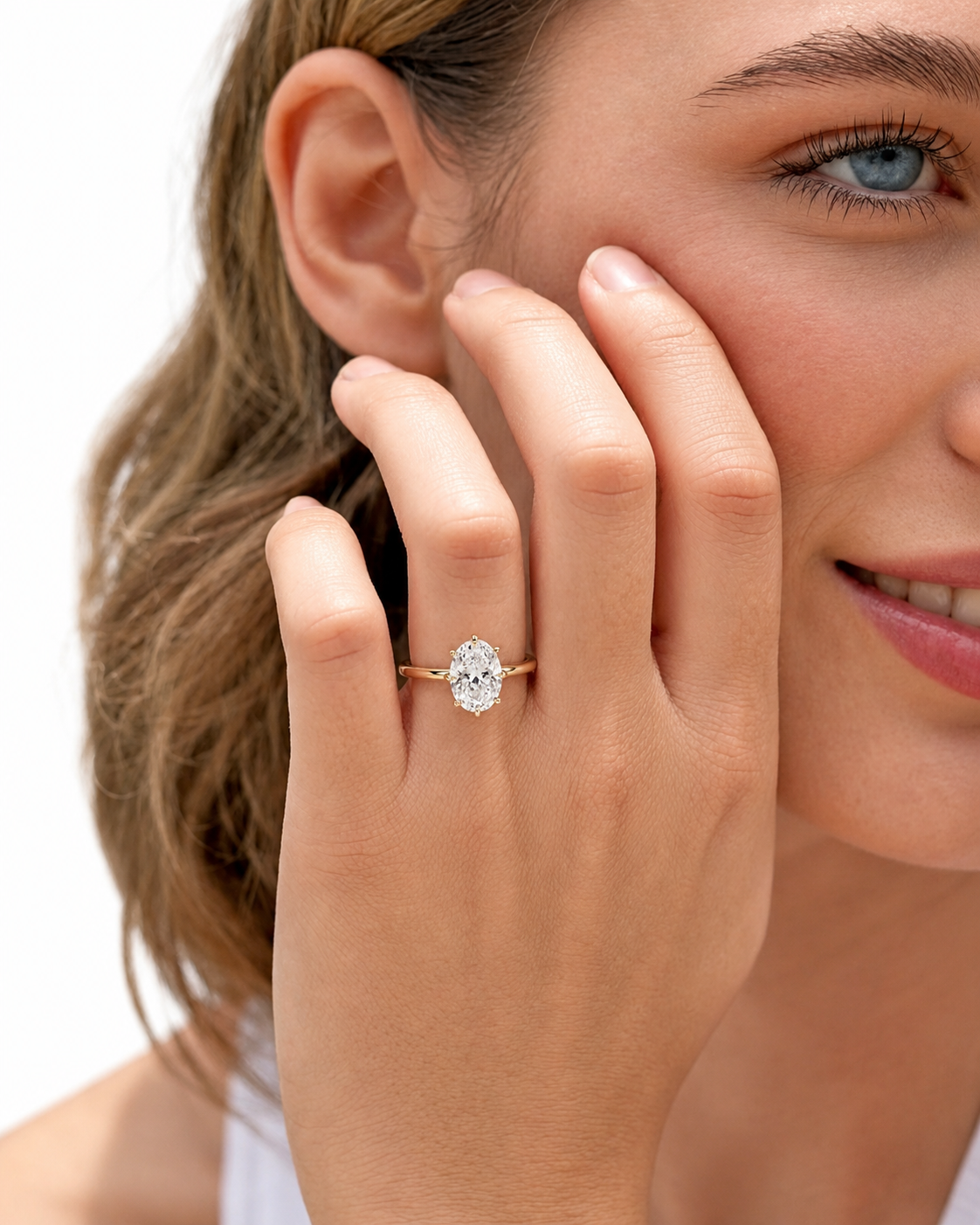 color_10K_YG, color_14K_YG &&A close-up lifestyle shot of a woman wearing a gold engagement ring with a round-cut clear gemstone on her finger, set against a clean white background.
