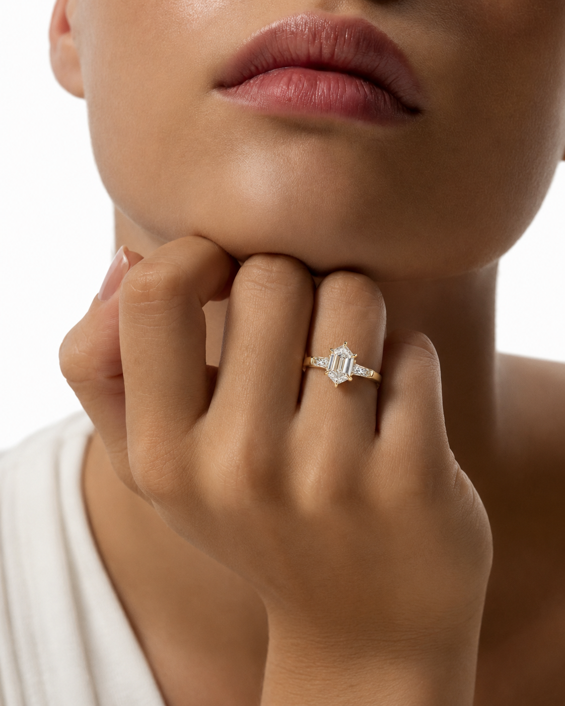 color_10K_YG, color_14K_YG &&A close-up lifestyle shot of a model wearing a diamond engagement ring with a baguette-cut center stone and small side stones on a gold band.