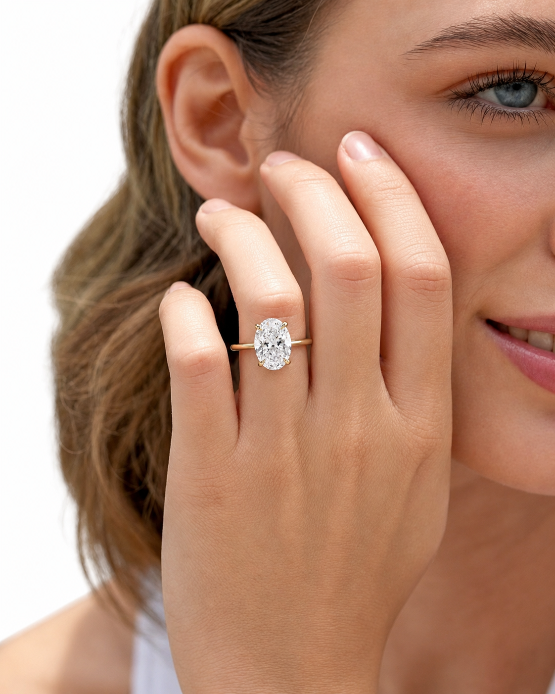 color_10K_YG, color_14K_YG &&A close-up lifestyle shot of a woman wearing a gold engagement ring with a round brilliant-cut diamond. The ring is shown on her finger, with her face partially visible against a clean white background.